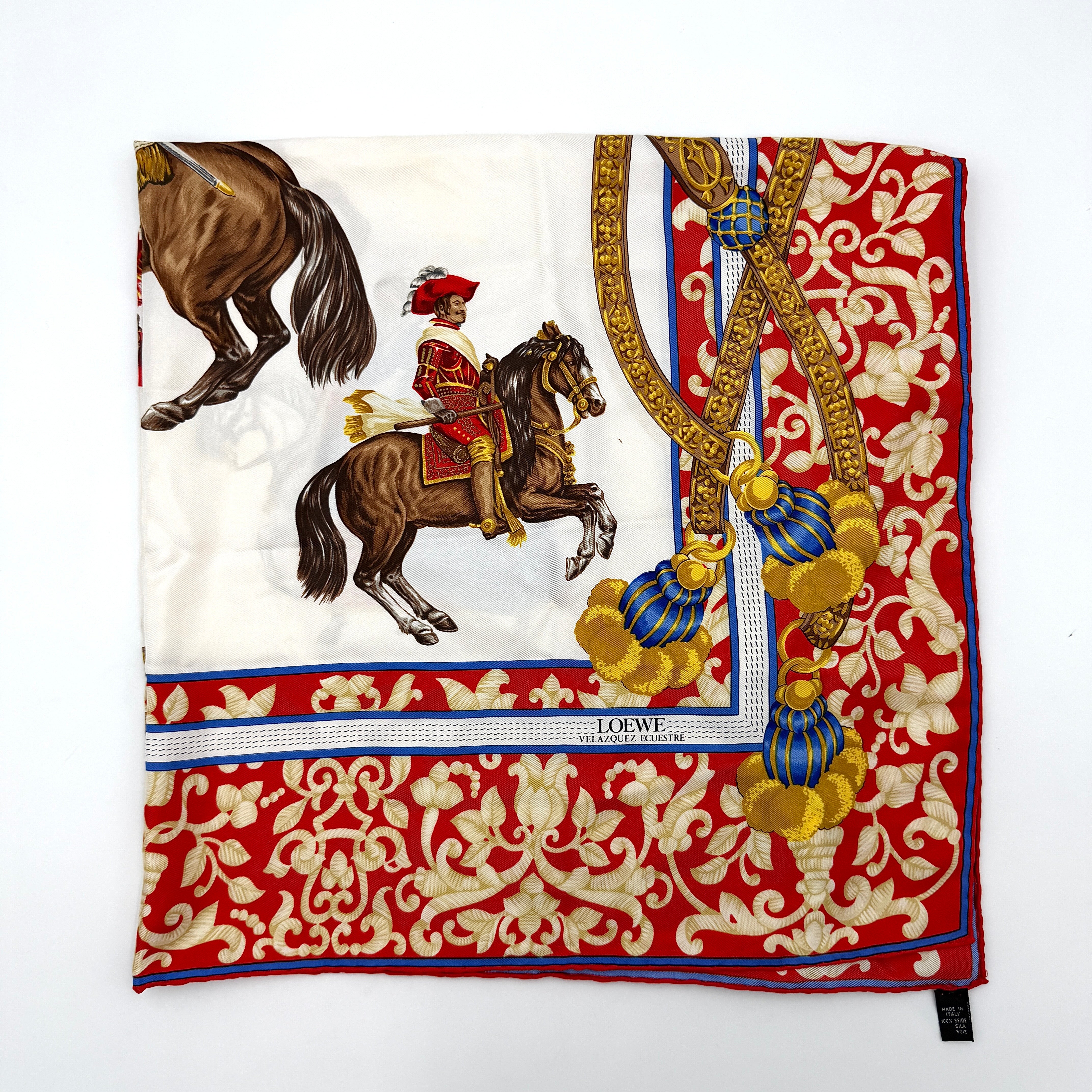 Loewe Velazquez Ecuestre silk scarf adorned with ornate red and gold baroque motifs and equestrian figures in rich multicolor.