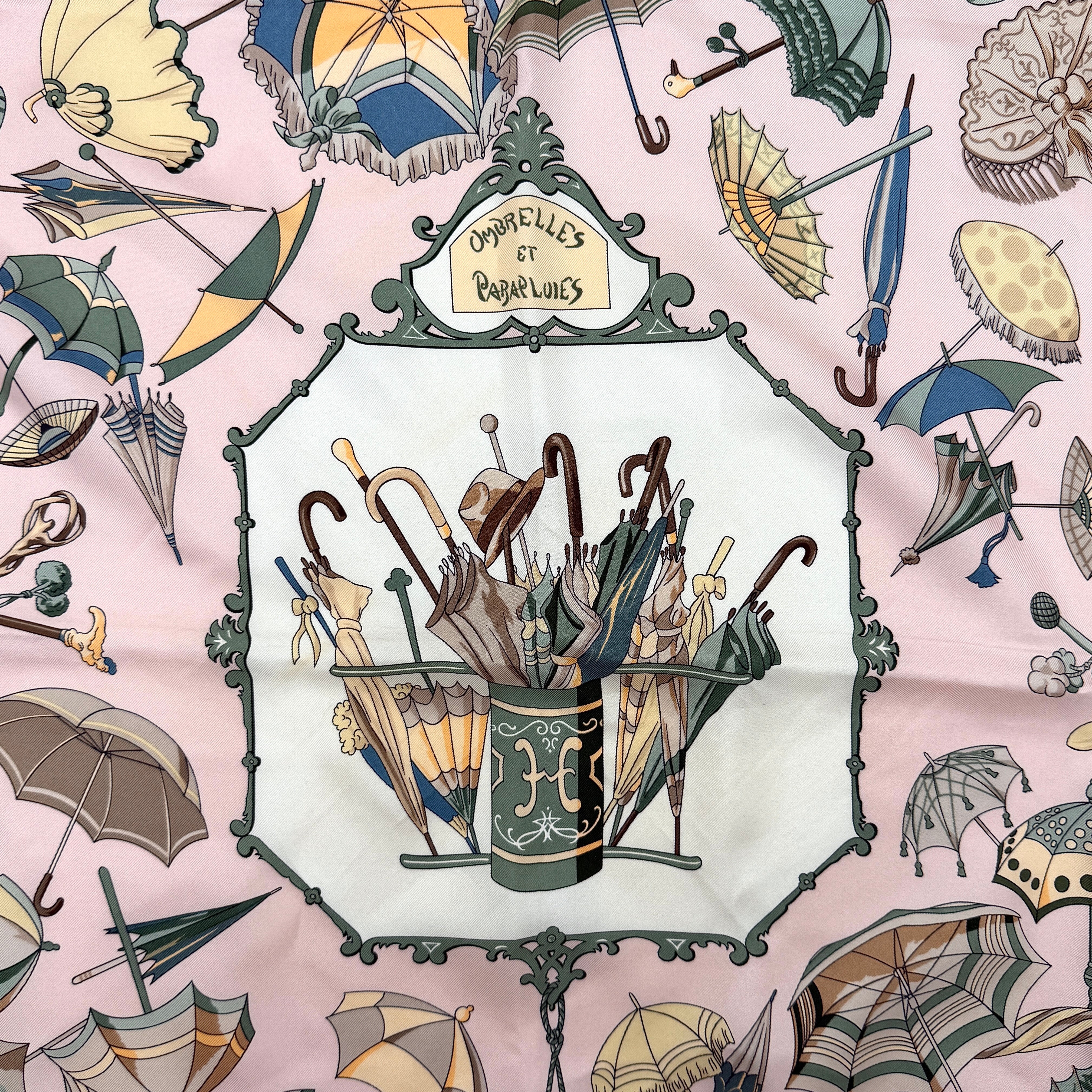 Hermès Ombrelles et Parapluies silk scarf in pink with umbrella print and illustrated figures, gracefully draped to show the intricate design.