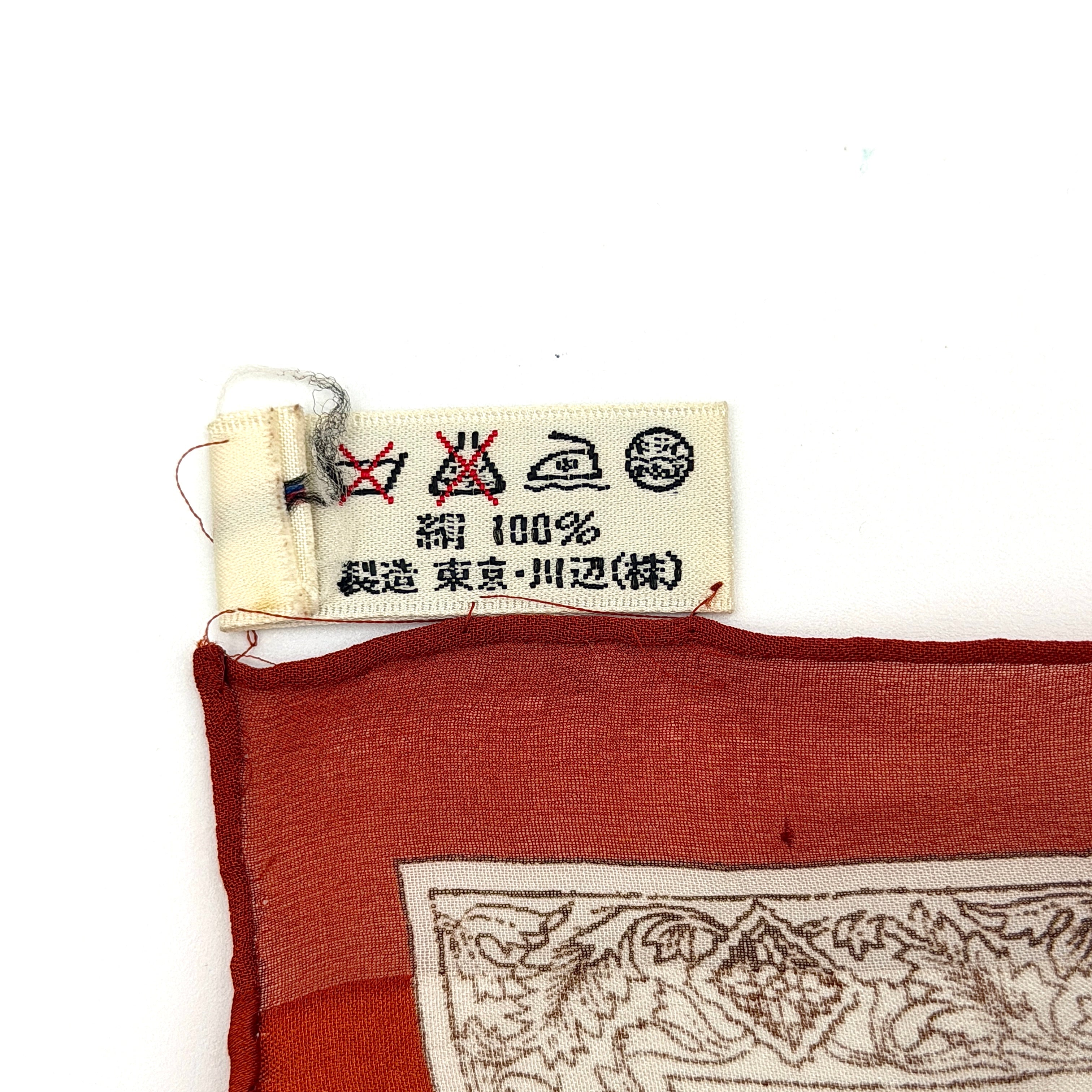 Saint Laurent silk scarf in rich red, featuring intricate cream floral designs and ornate borders with the YSL monogram visibly displayed.