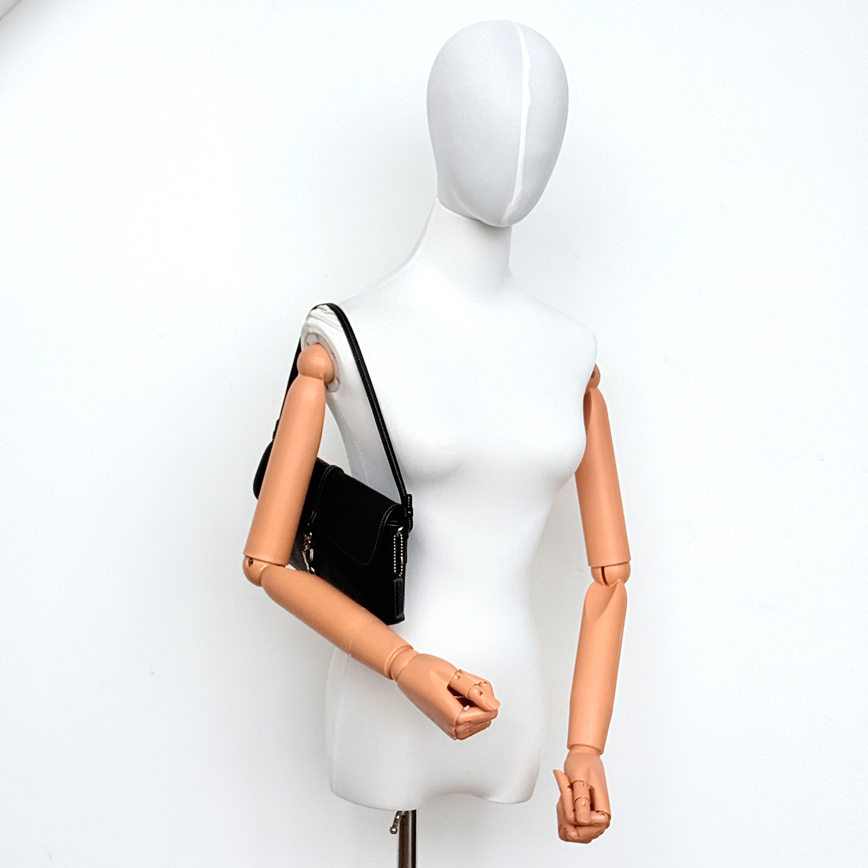 Coach black leather Y2K Demi Clip baguette shoulder bag with silver-tone hardware and contrast stitching, shown on a flat surface.