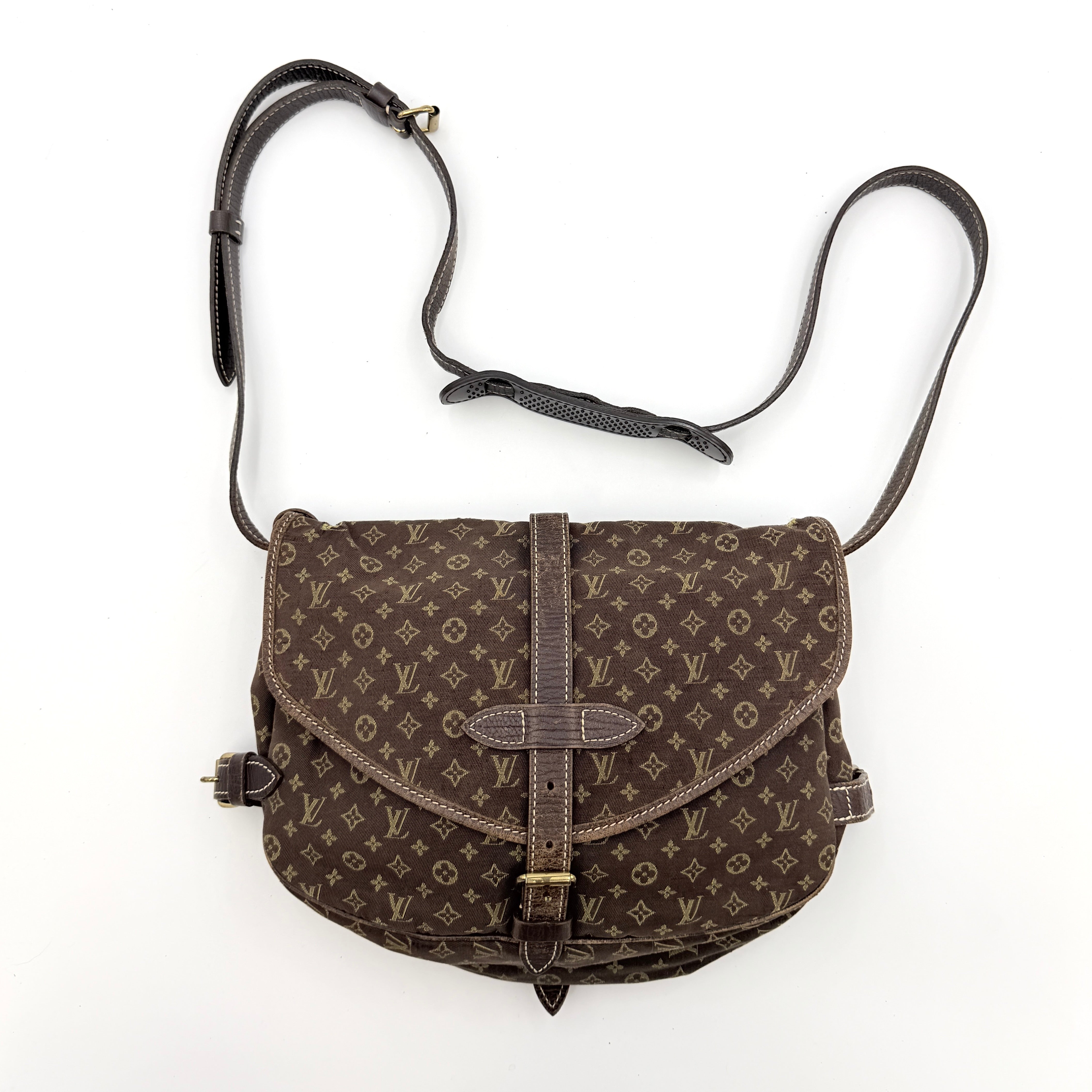 Louis Vuitton Monogram Mini Lin Saumur 30 in brown canvas with monogram pattern and leather buckled strap, photographed with the crossbody strap extended.