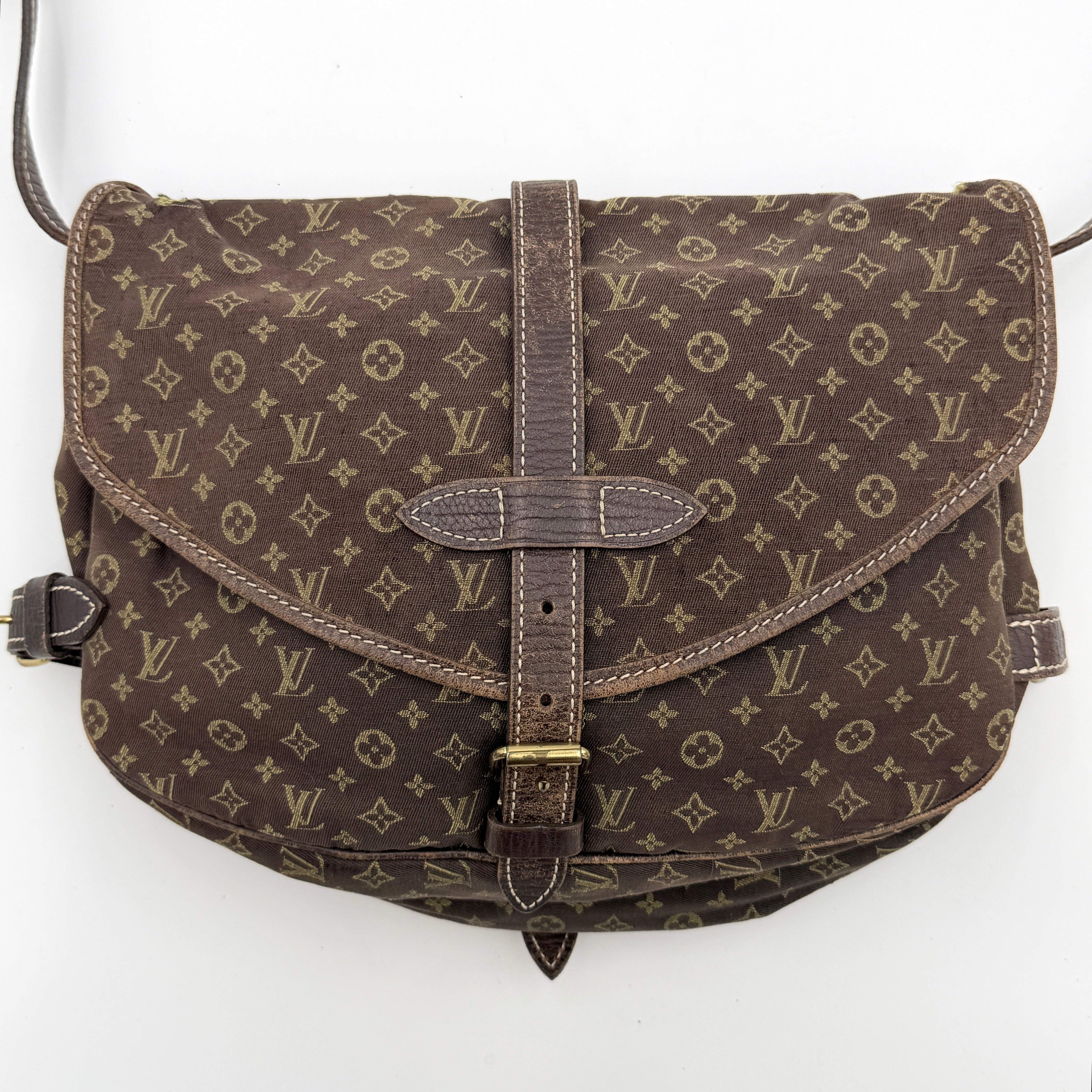 Louis Vuitton Monogram Mini Lin Saumur 30 in brown canvas with monogram pattern and leather buckled strap, photographed with the crossbody strap extended.