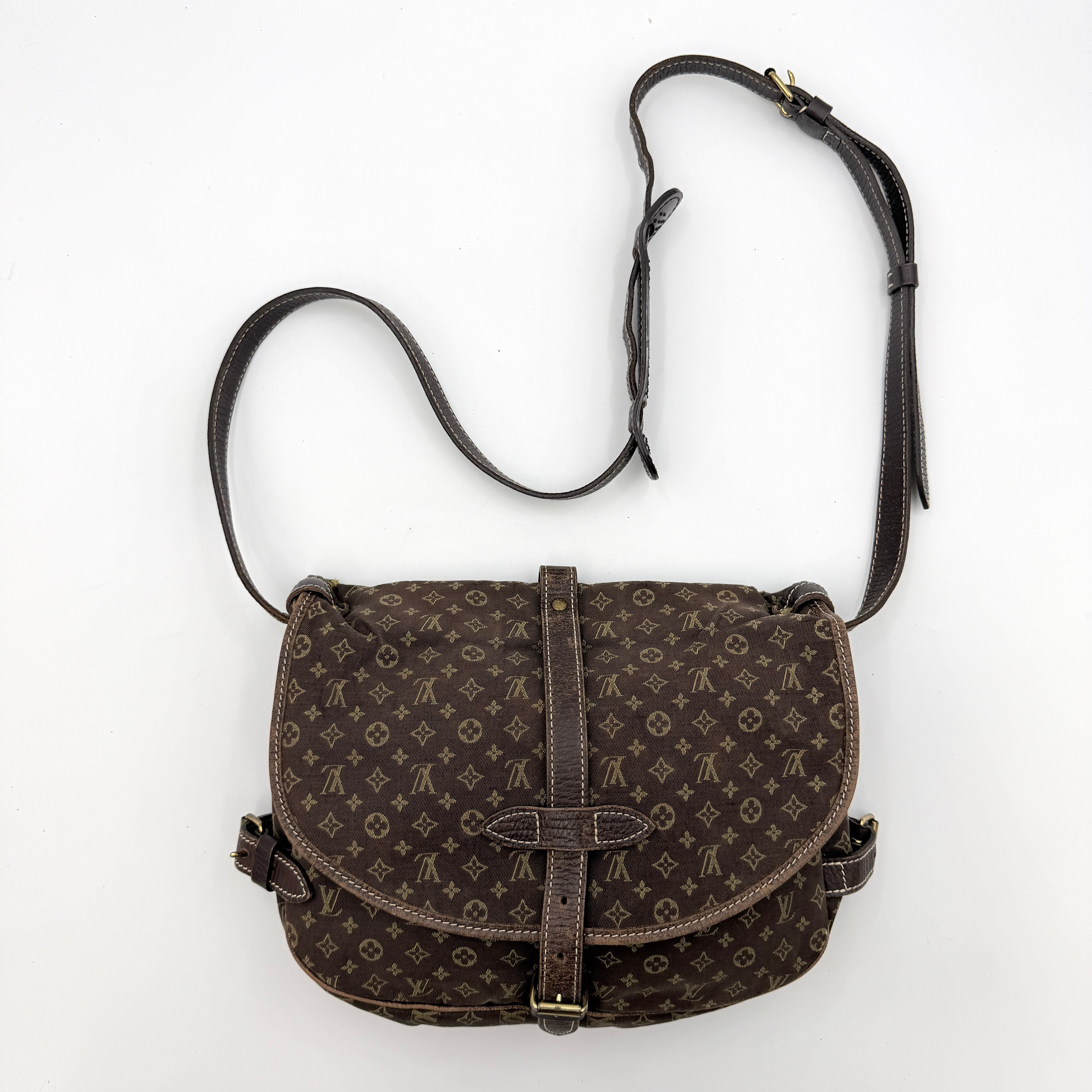 Louis Vuitton Monogram Mini Lin Saumur 30 in brown canvas with monogram pattern and leather buckled strap, photographed with the crossbody strap extended.
