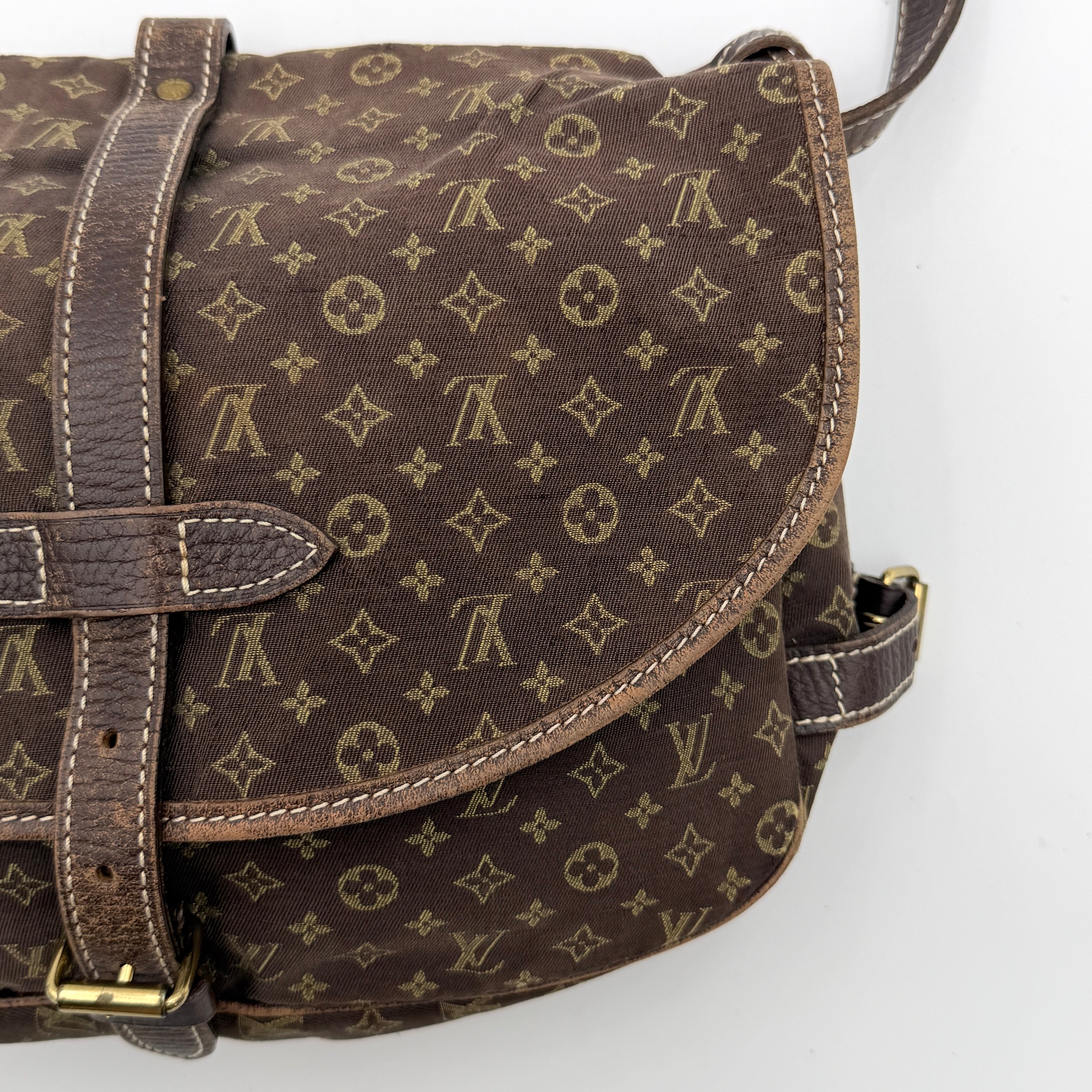 Louis Vuitton Monogram Mini Lin Saumur 30 in brown canvas with monogram pattern and leather buckled strap, photographed with the crossbody strap extended.