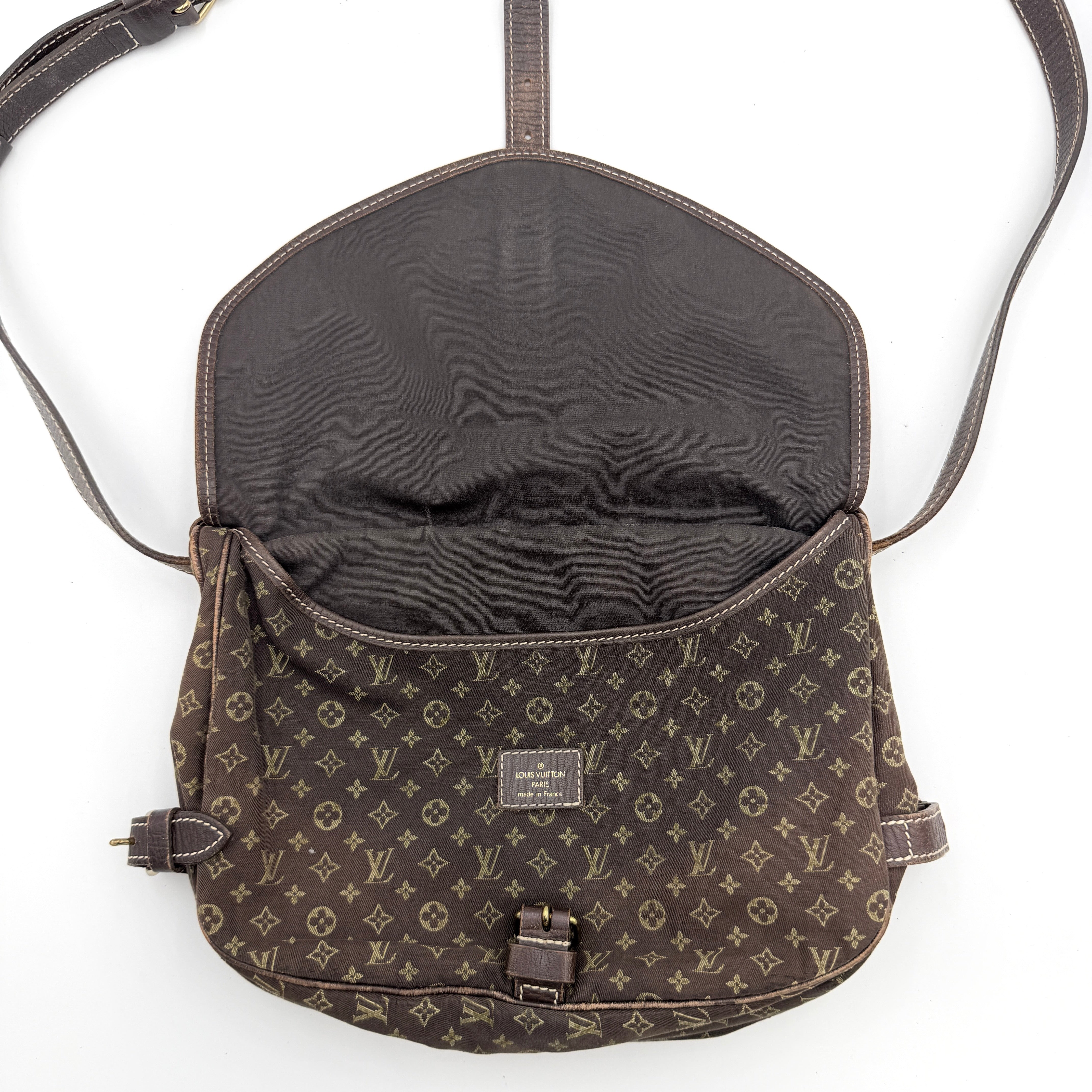 Louis Vuitton Monogram Mini Lin Saumur 30 in brown canvas with monogram pattern and leather buckled strap, photographed with the crossbody strap extended.