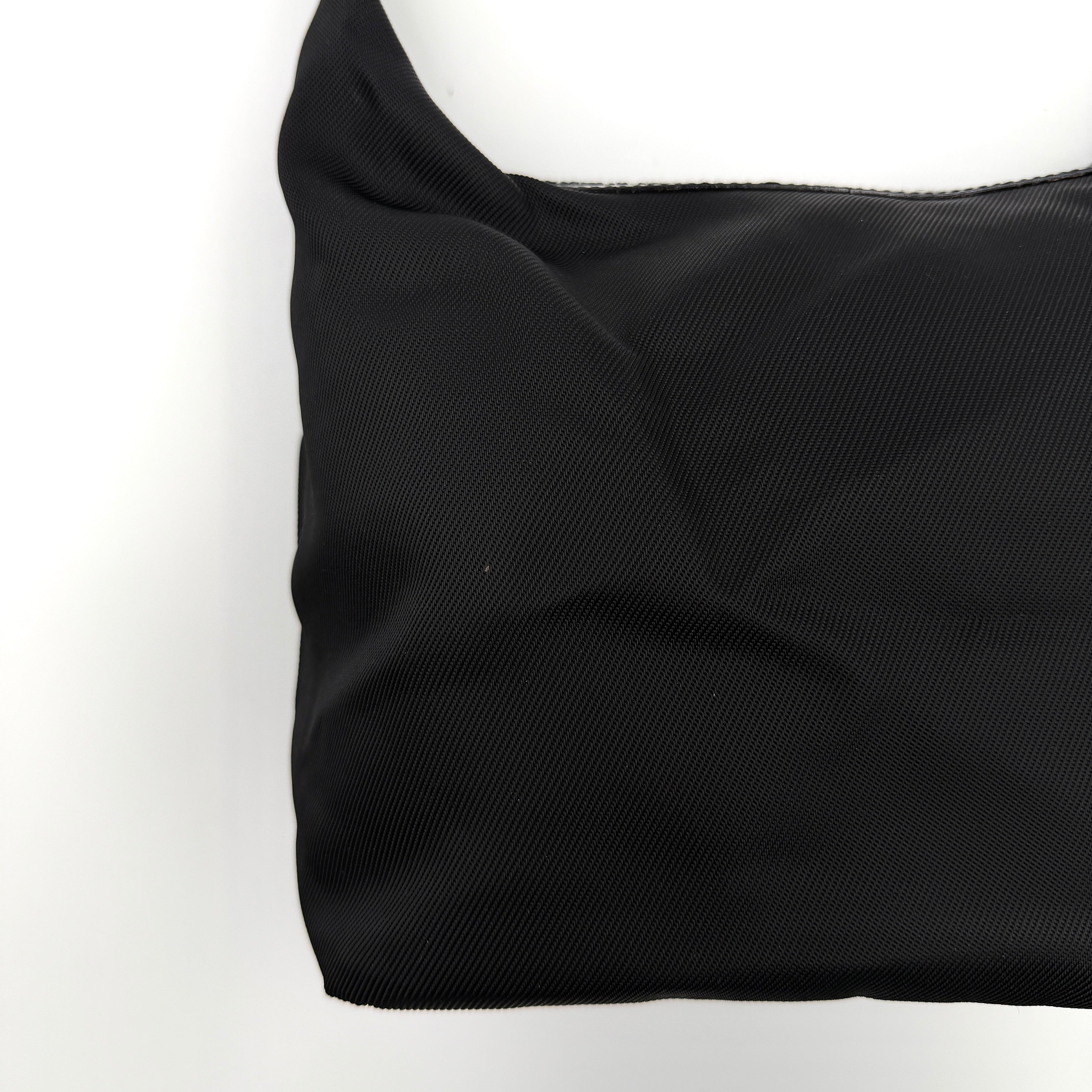Gucci black nylon shoulder bag with a sculpted bamboo top handle and sleek silhouette against a white background.