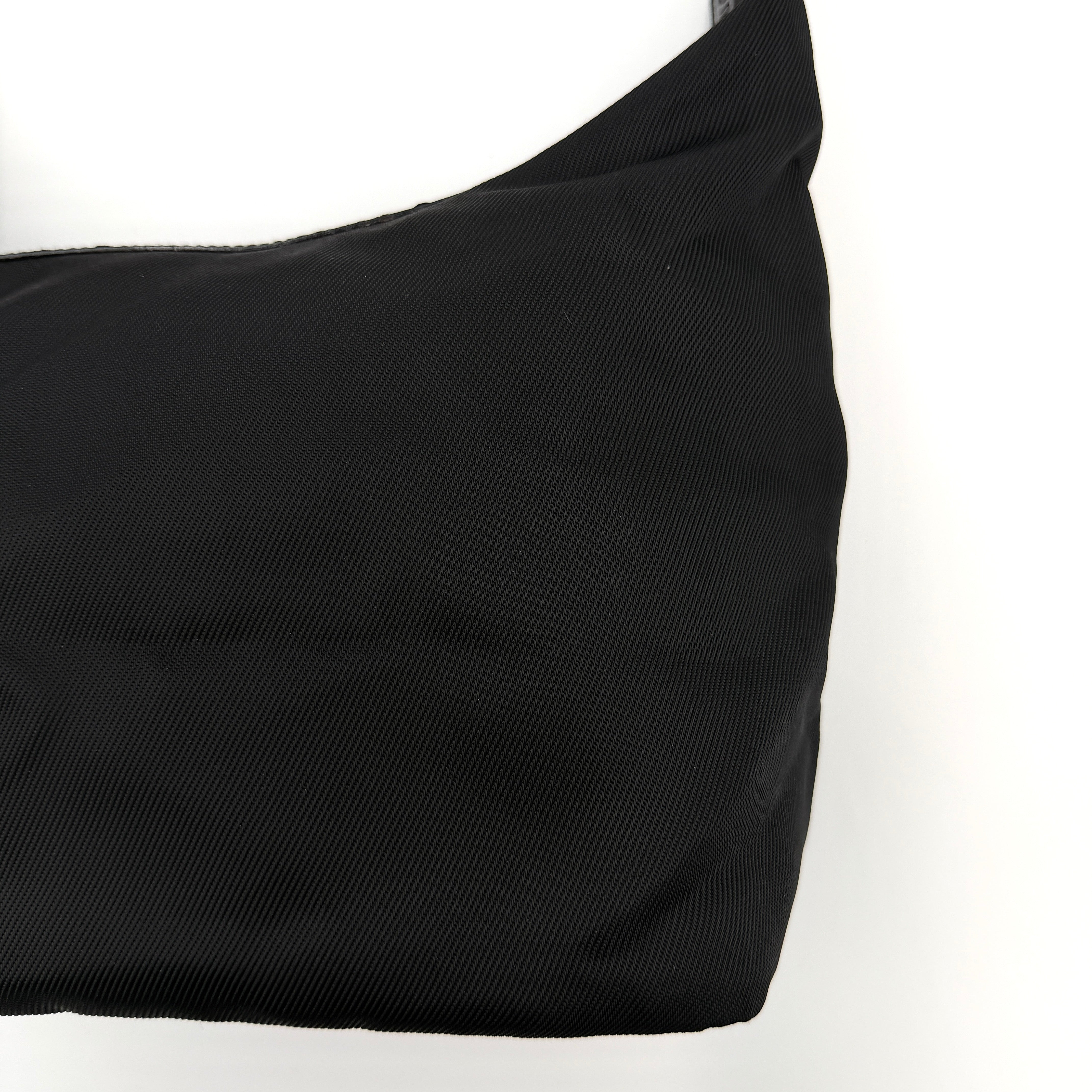 Gucci black nylon shoulder bag with a sculpted bamboo top handle and sleek silhouette against a white background.
