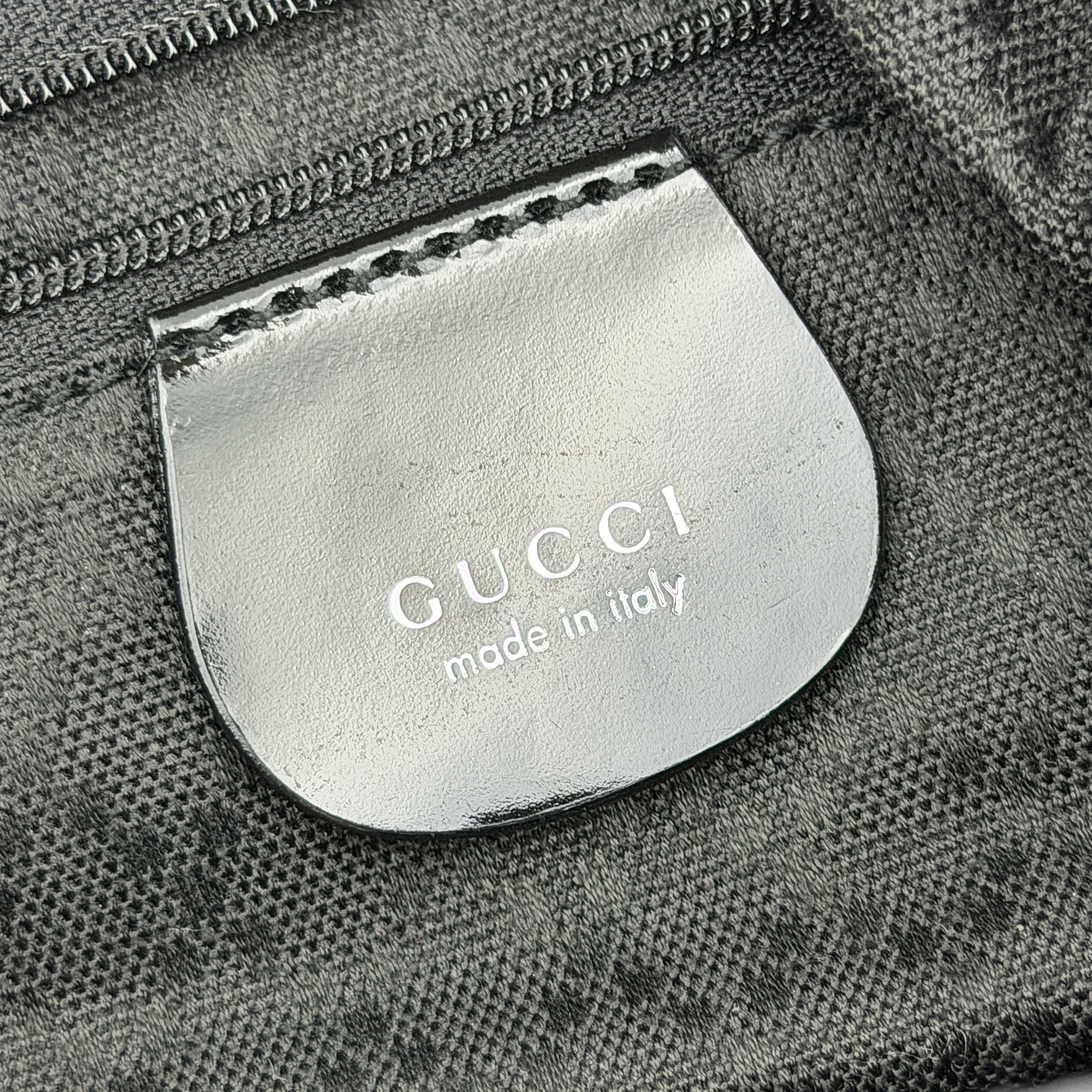 Gucci black nylon shoulder bag with a sculpted bamboo top handle and sleek silhouette against a white background.