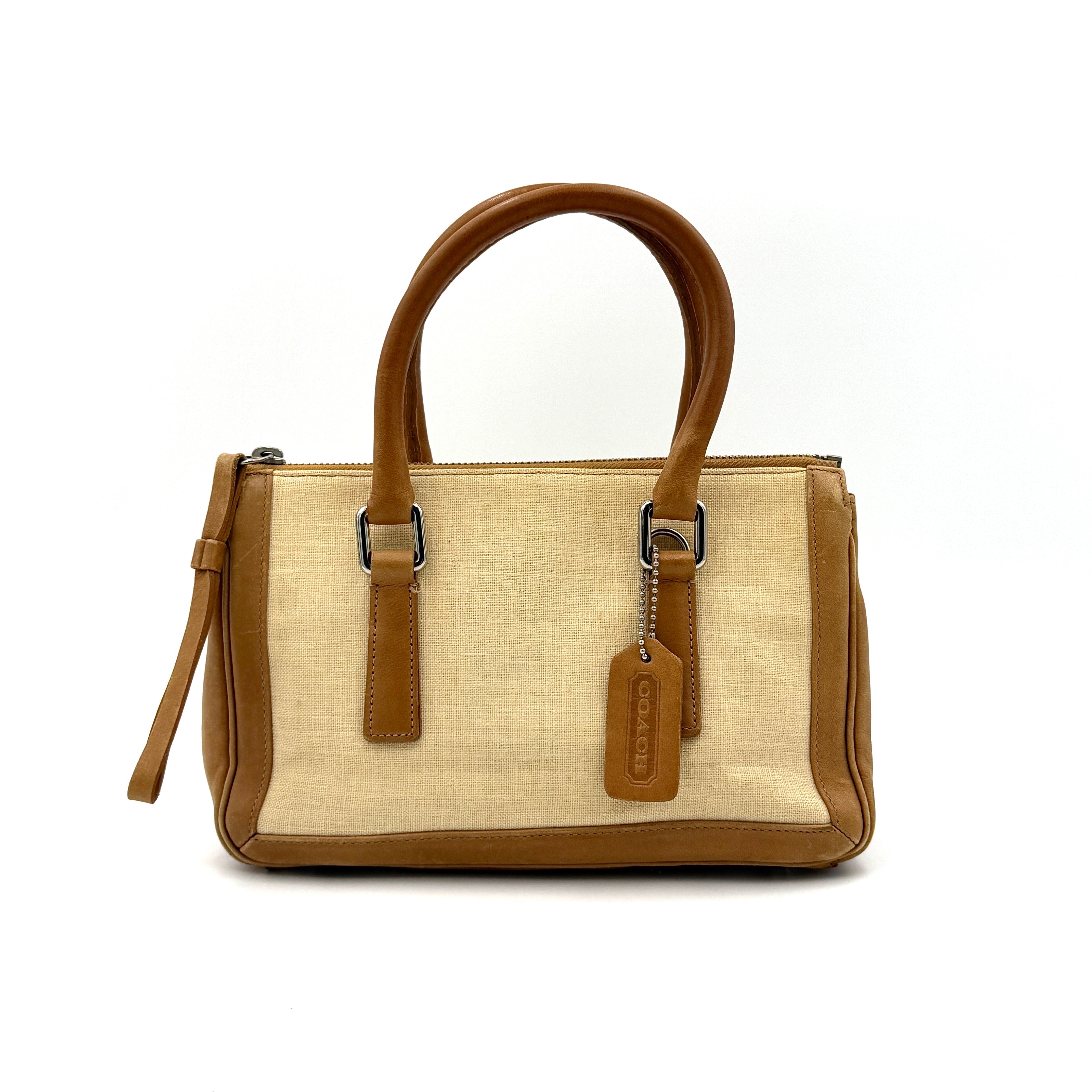 Coach Bonnie Legacy Satchel in beige canvas with caramel leather trim, structured silhouette and dual rolled handles.