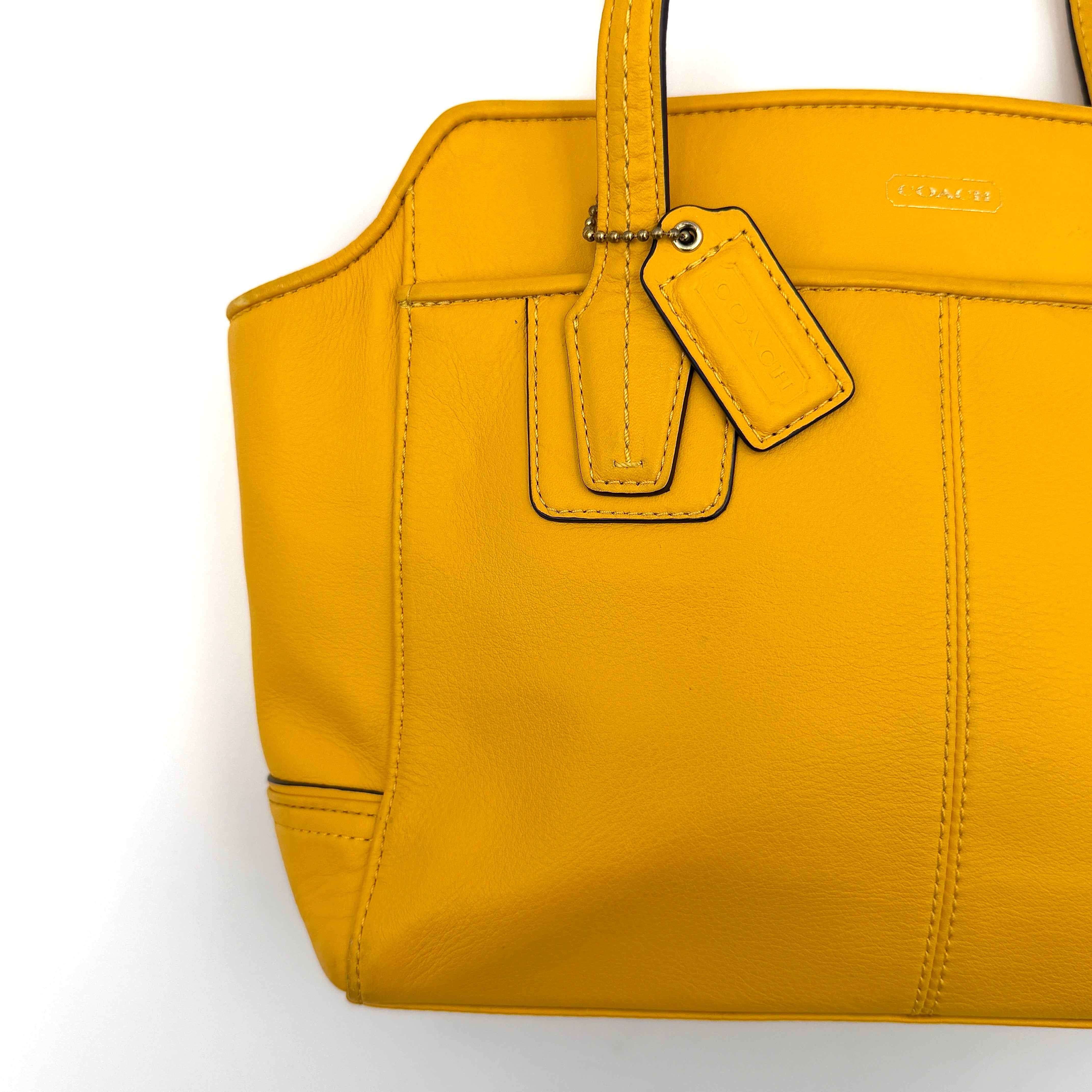 Coach Taylor Bette Mini Tote Bag in vibrant yellow leather with double top handles and detachable shoulder strap displayed beside it.