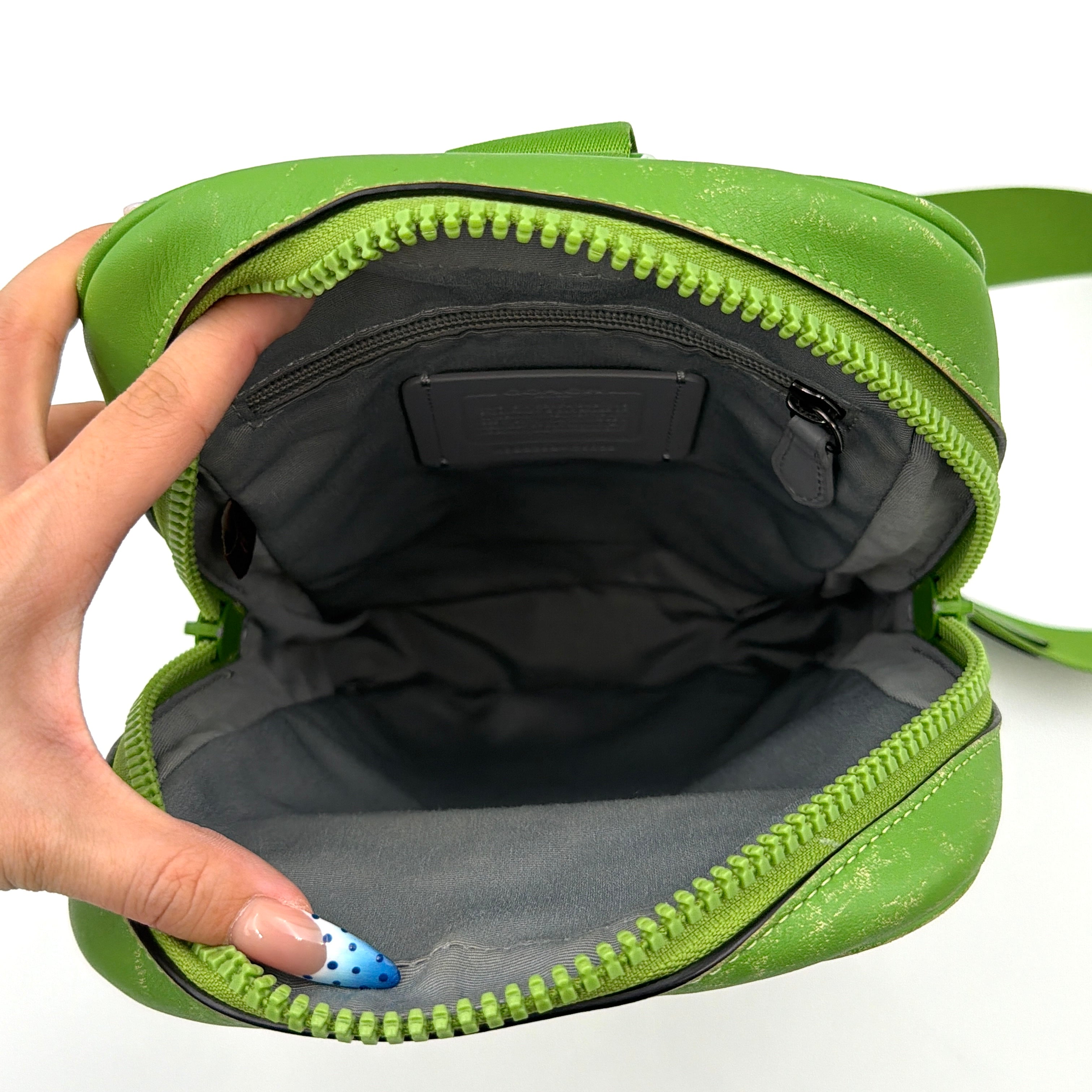 Coach Signature Canvas Track Pack Crossbody Bag in vibrant green with tonal green hardware and adjustable strap set against a clean background.