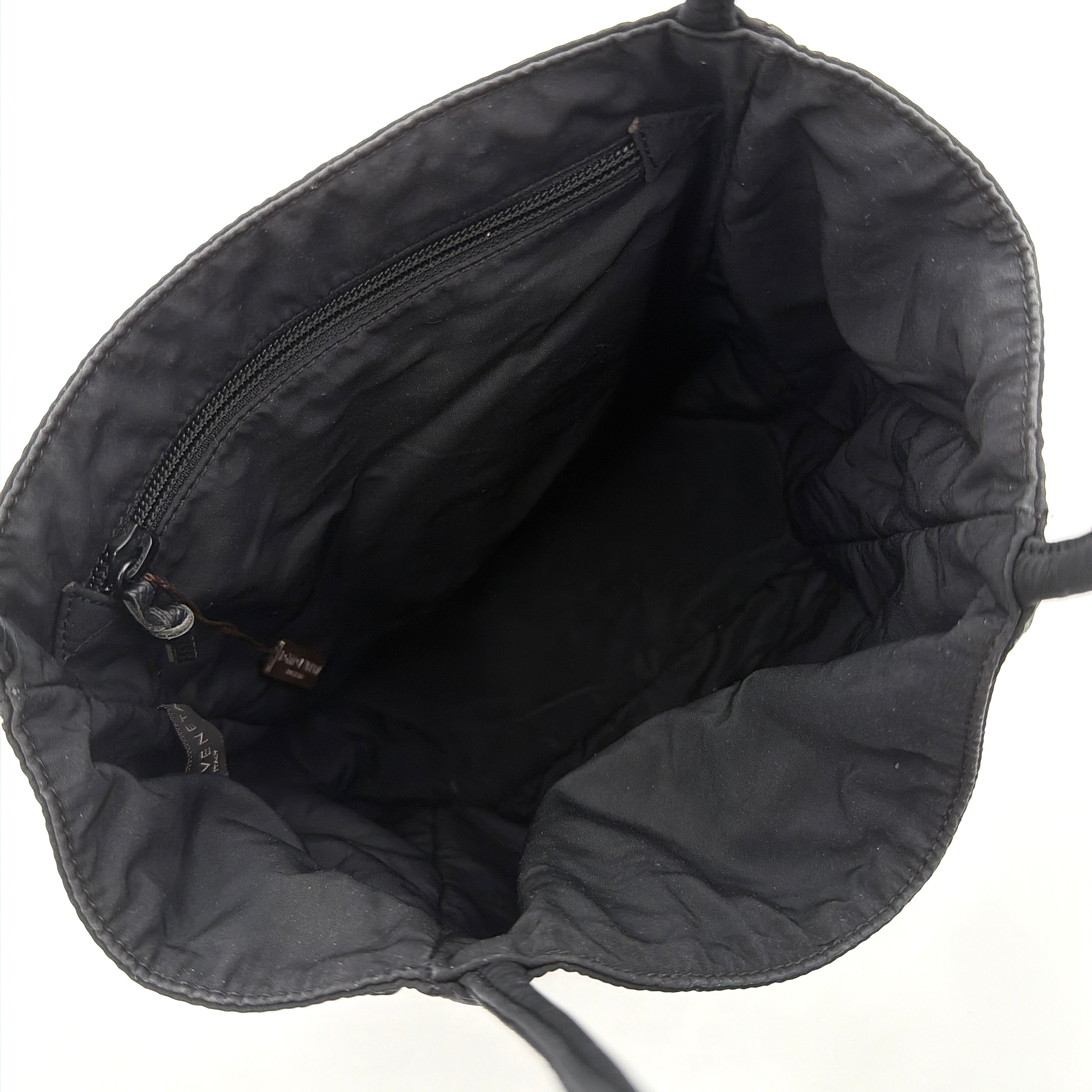 Bottega Veneta black nylon tote with structured double handles and a pale gold-tone logo plaque at the front.
