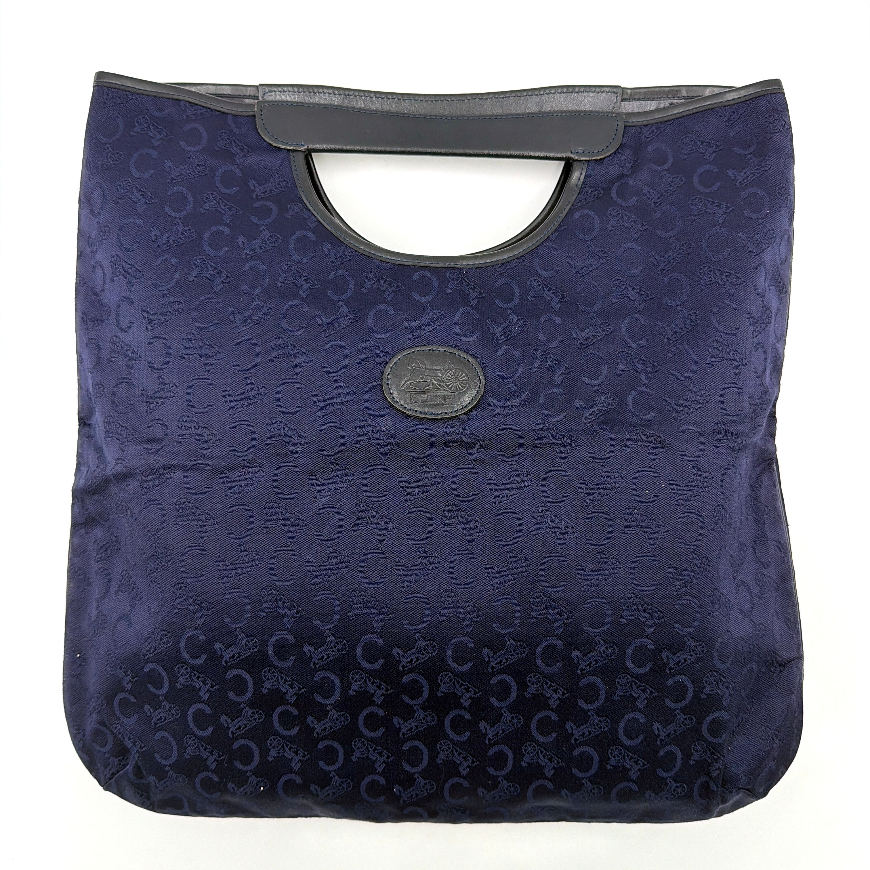 Celine Noevir Macadam Foldover Tote in navy jacquard with carriage motif, leather trim and cutout handles, photographed against a white background.