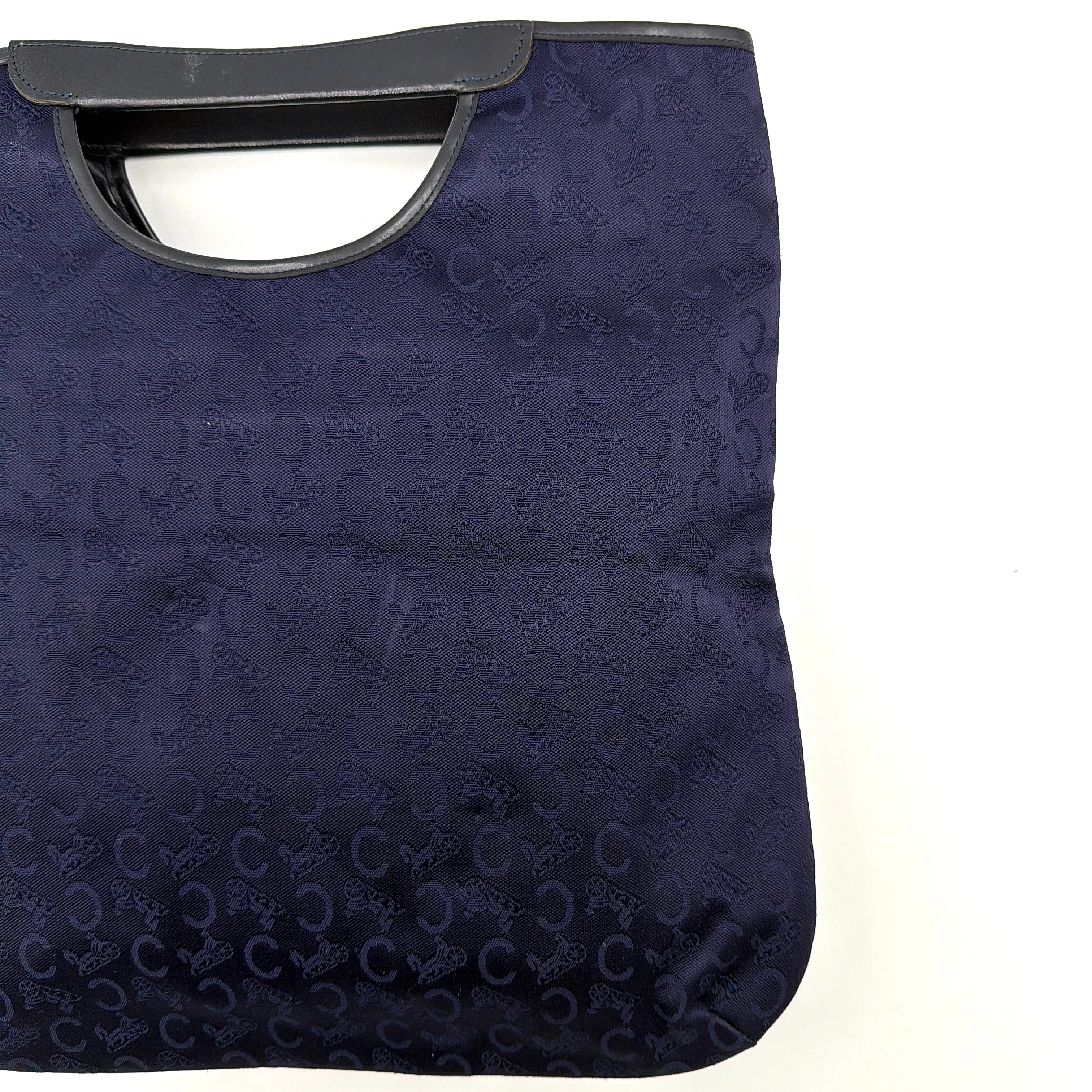 Celine Noevir Macadam Foldover Tote in navy jacquard with carriage motif, leather trim and cutout handles, photographed against a white background.