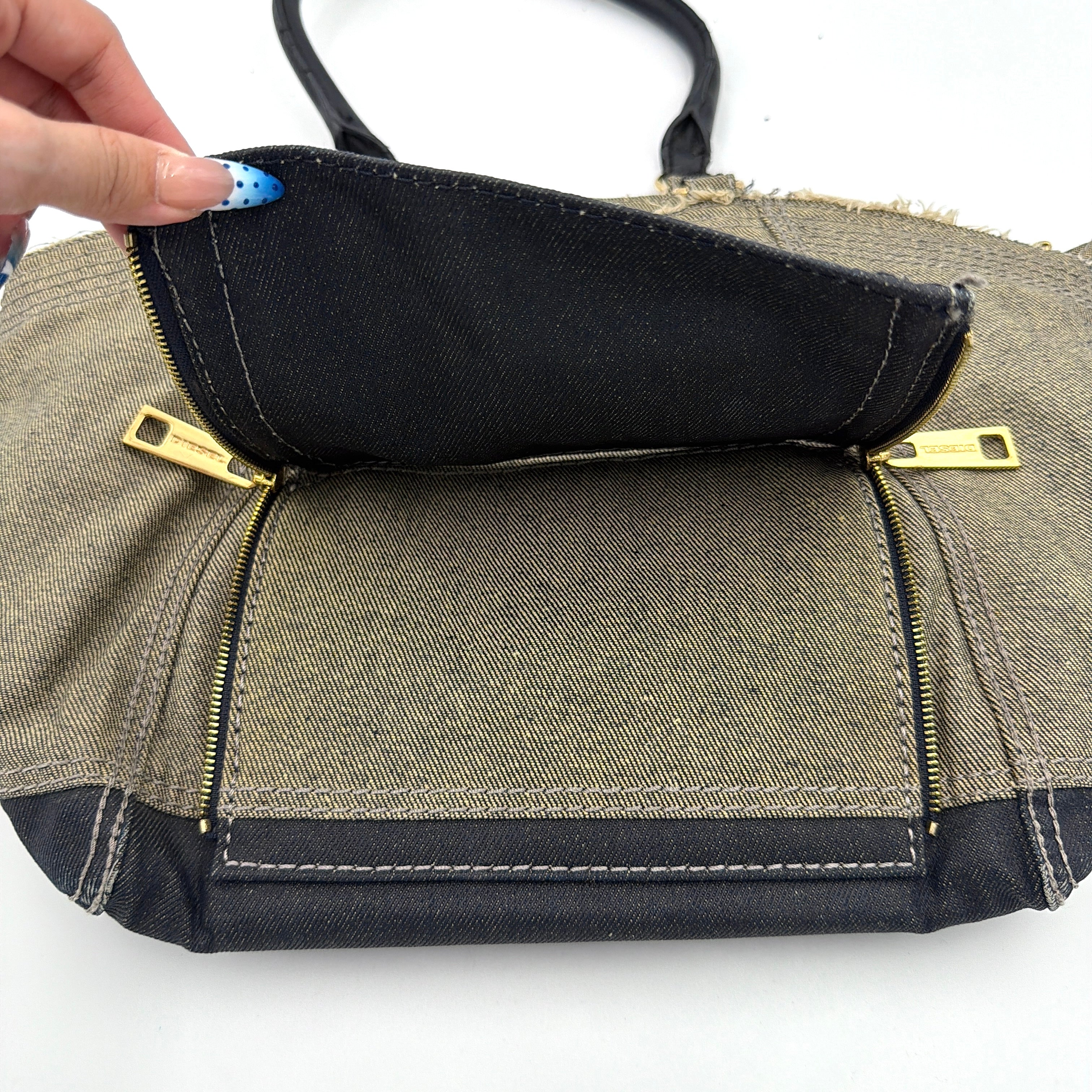 Diesel washed denim shoulder bag with black leather handles, gold zips and frayed edge detail.