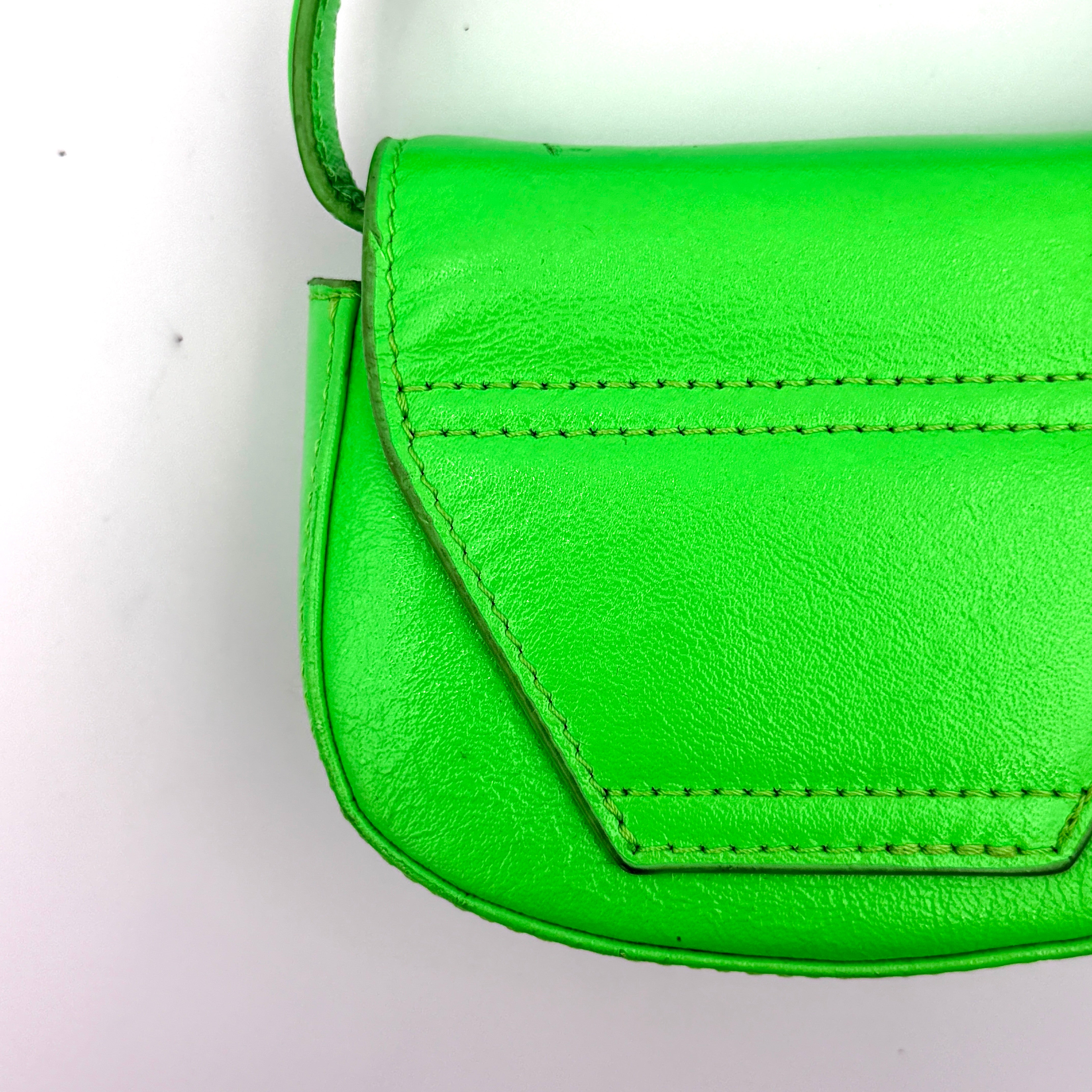 Diesel 1DR-XS Mini Bag in vivid neon green leather with bold silver D plaque and detachable strap, presented against a clean background.