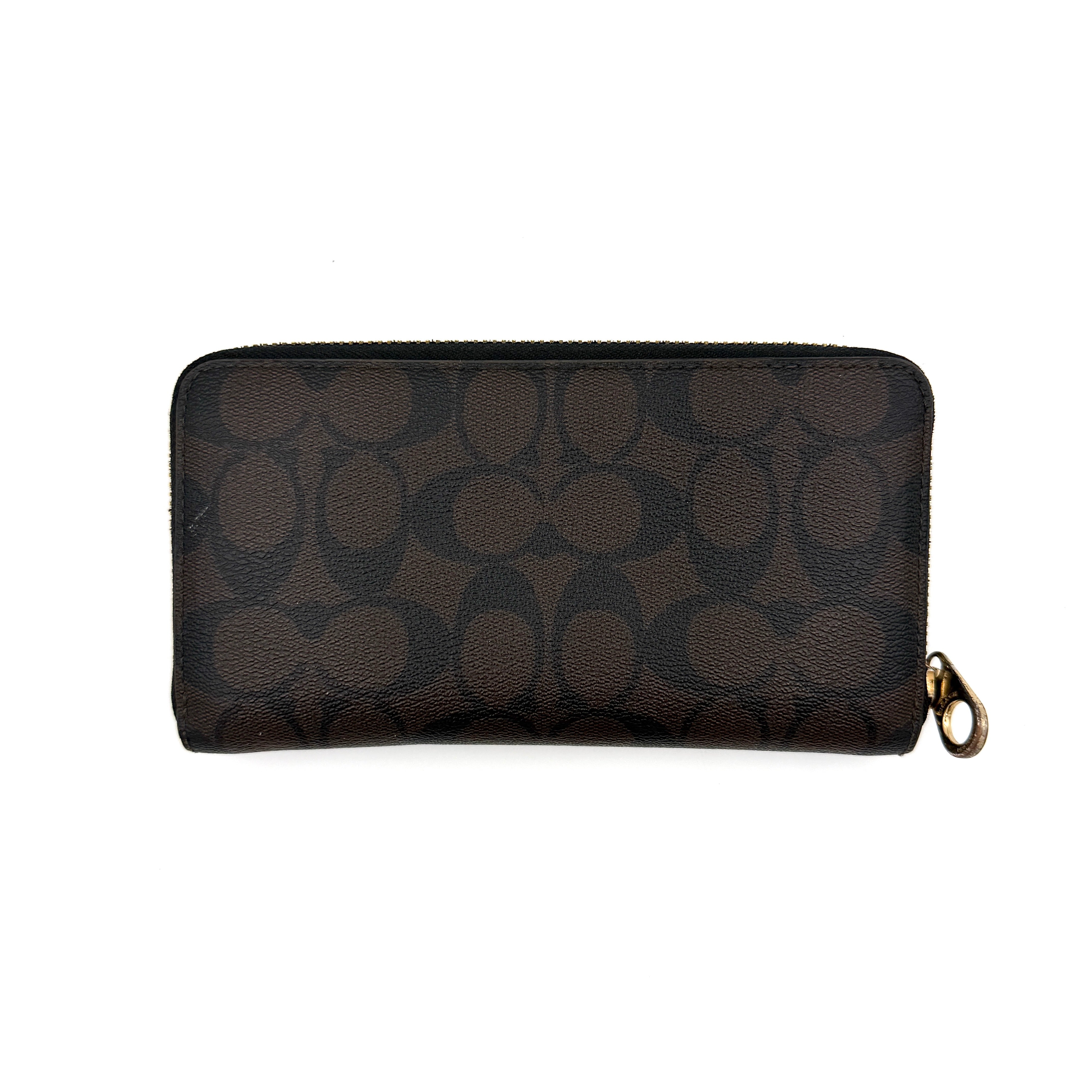 Coach Signature Canvas long wallet in brown monogram with gold zip and logo, shown from the front against a clean background.