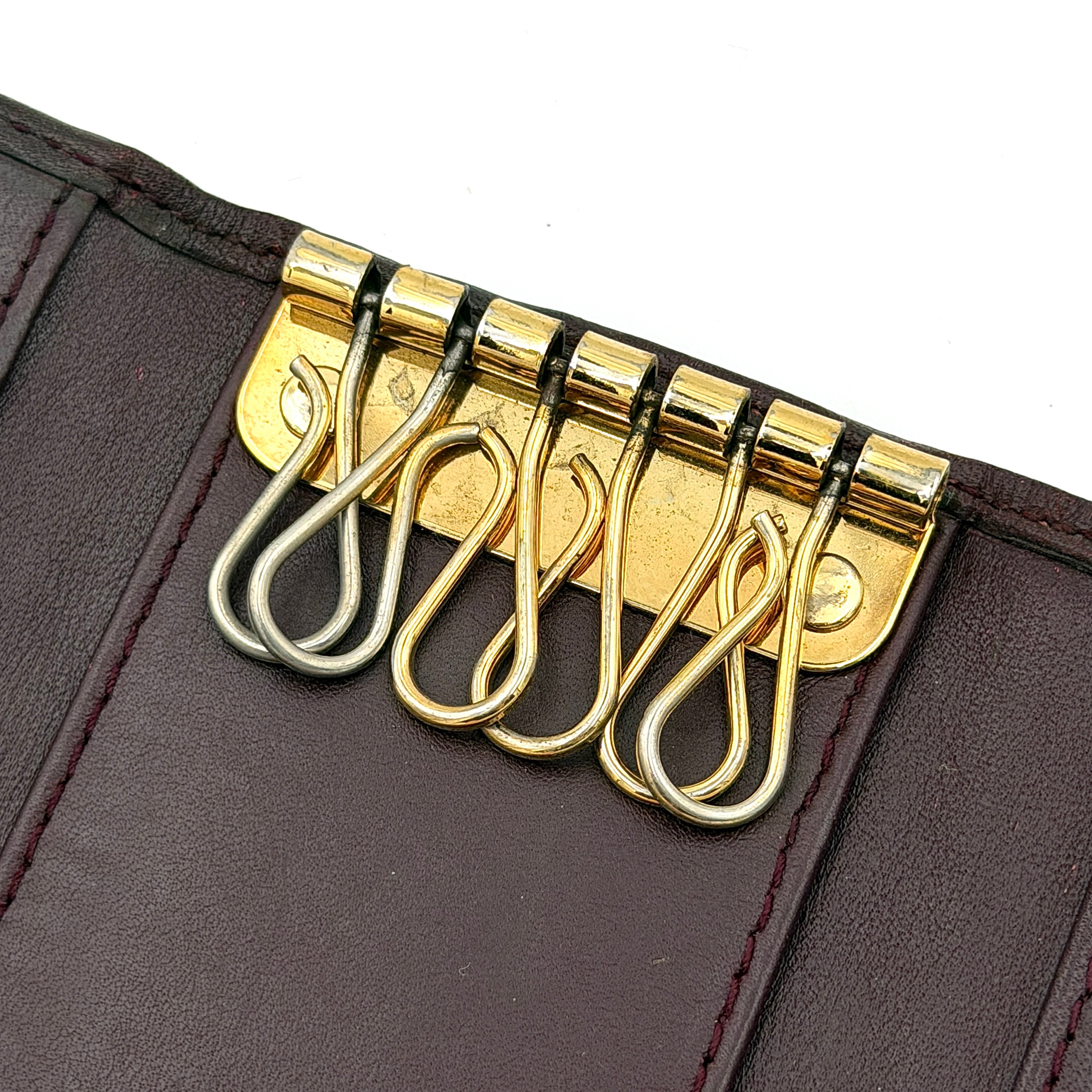 Dior Trotter Monogram key holder in red canvas with burgundy leather trim, photographed closed on a clean white background.