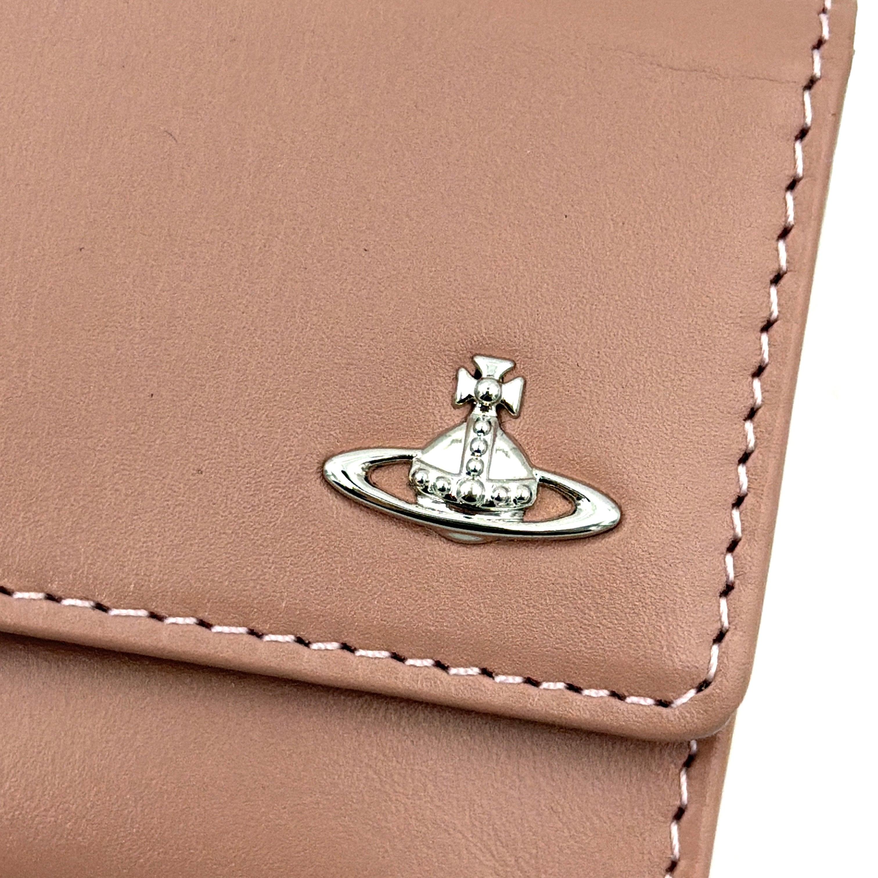 Vivienne Westwood pink leather wallet with silver signature Orb hardware, styled against a clean background.