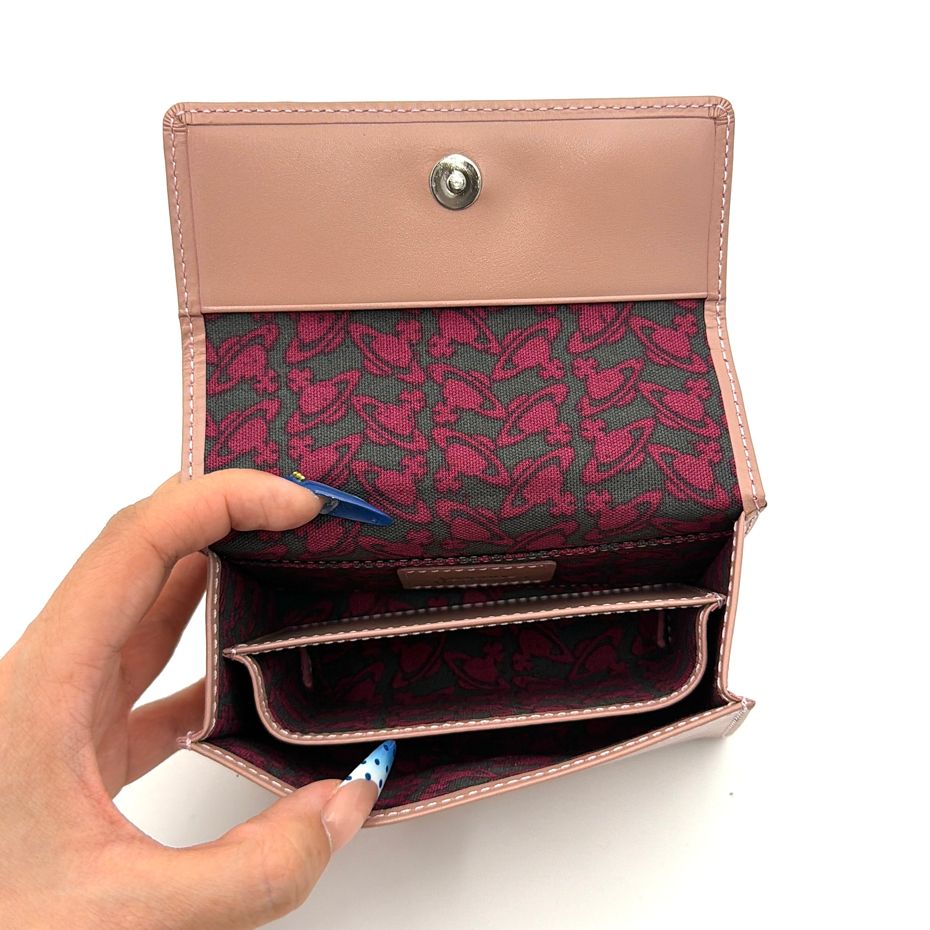 Vivienne Westwood pink leather wallet with silver signature Orb hardware, styled against a clean background.