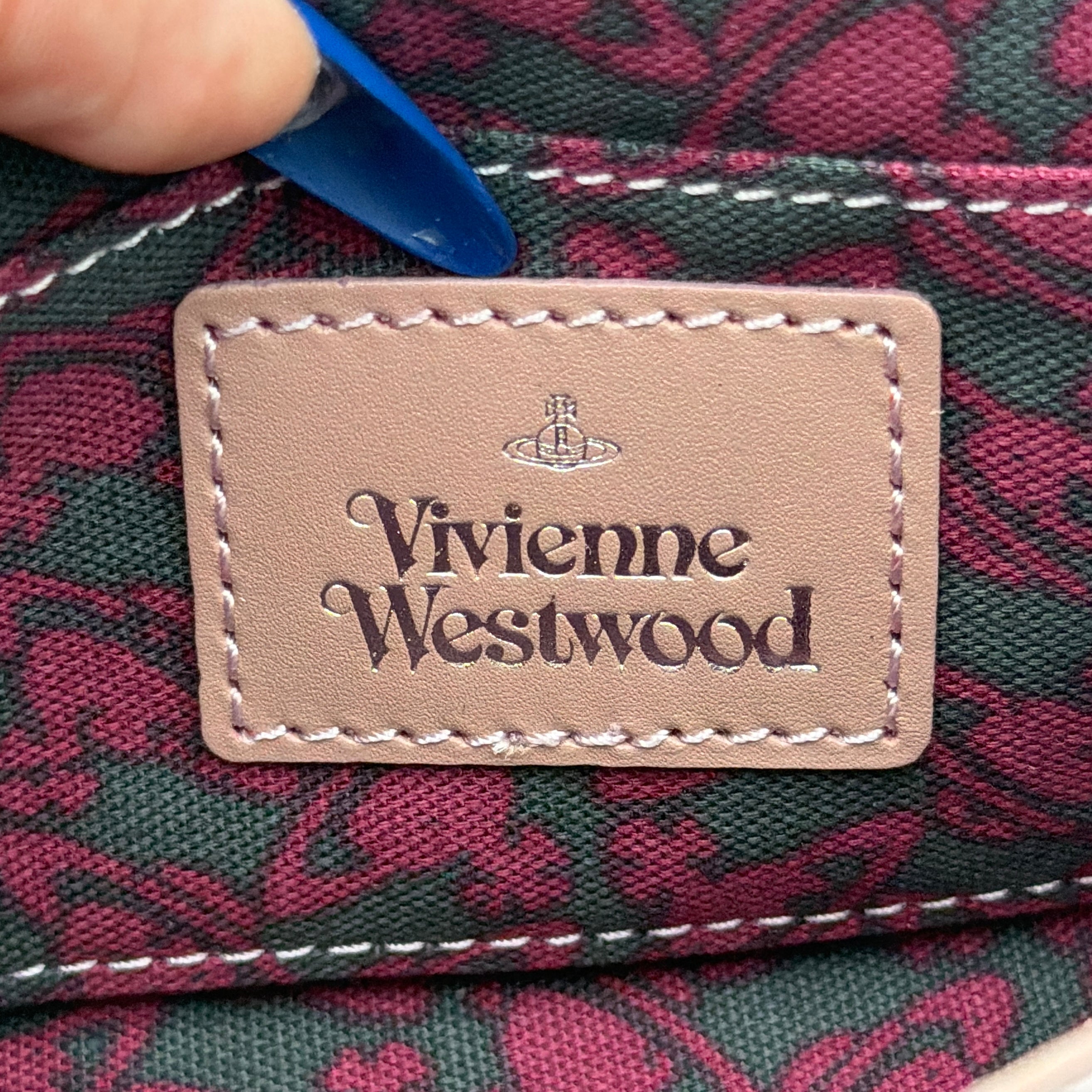 Vivienne Westwood pink leather wallet with silver signature Orb hardware, styled against a clean background.