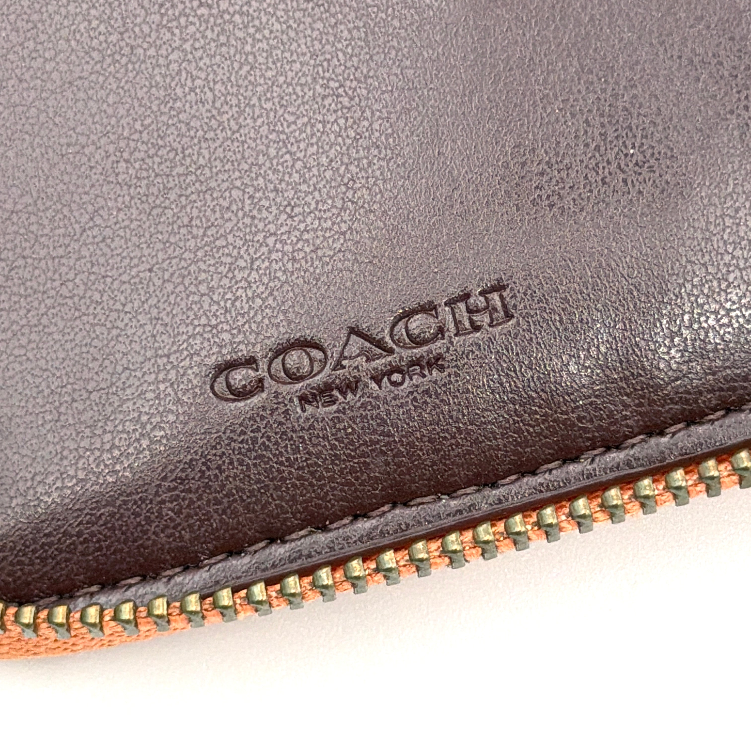 Coach Prairie Rivets Zip Around Small Wallet in orange pebbled leather with floral rivets and zip-around closure.