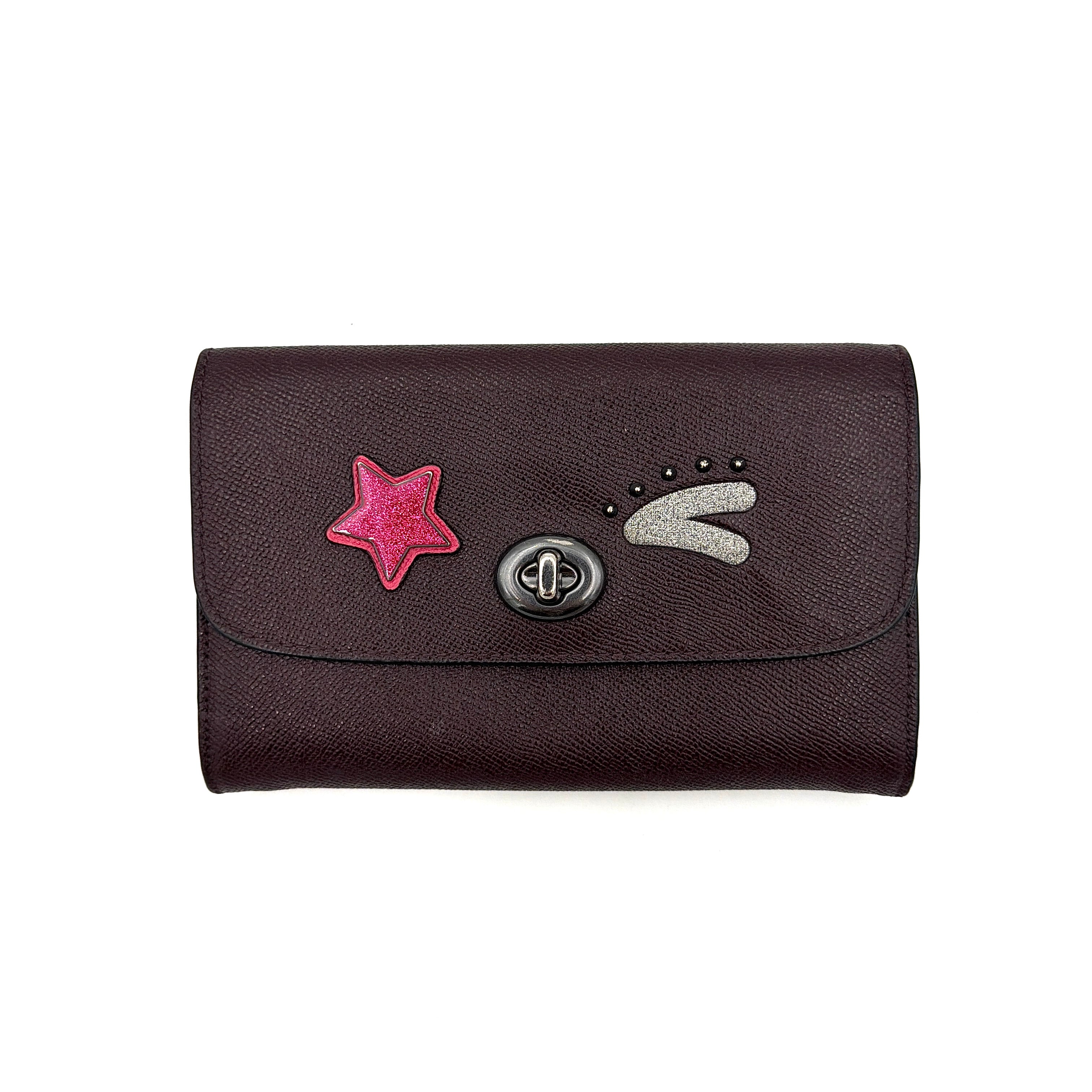 Coach Bear Turnlock Clutch in burgundy leather with playful pink and silver star details and signature gunmetal turnlock front closure.