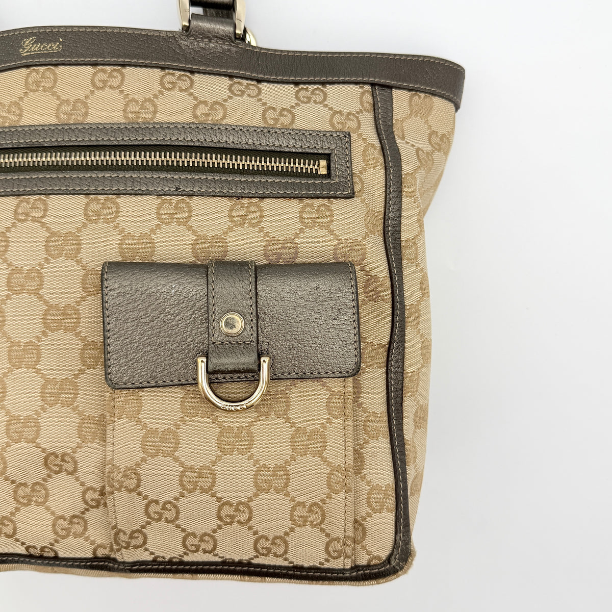 Gucci GG Monogram Abbey Pocket Tote Bag in beige and brown canvas with leather trim and front pockets, photographed against a white background.
