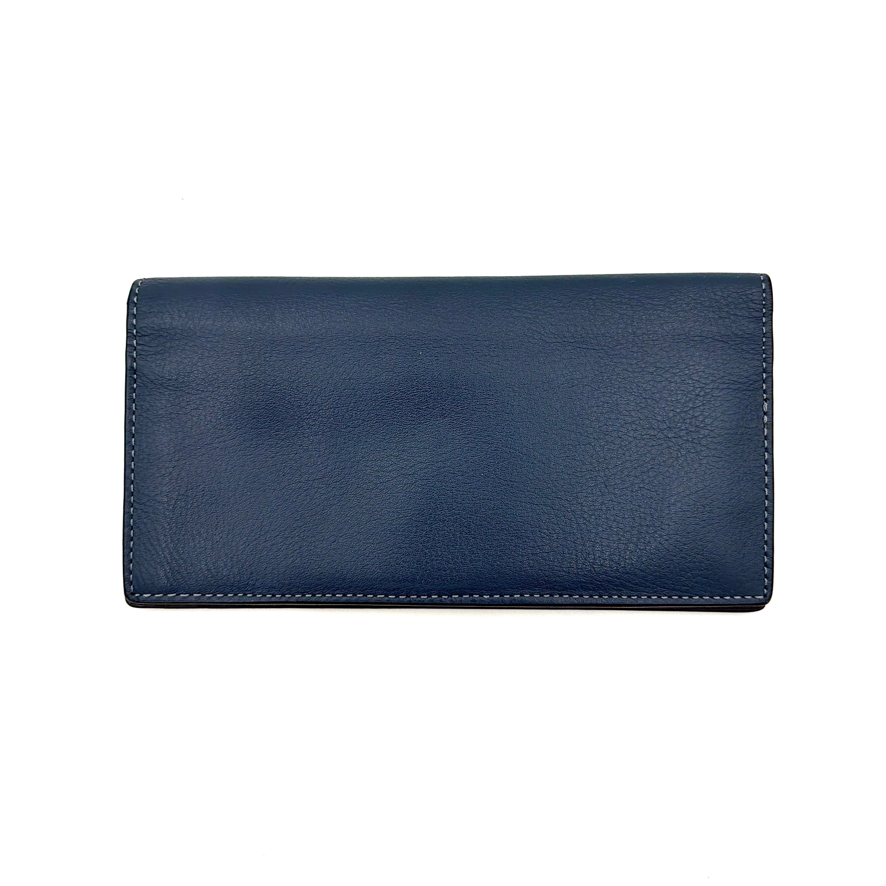 Coach Flap Long Wallet in navy blue leather with embossed logo, shown in a crisp editorial front view.