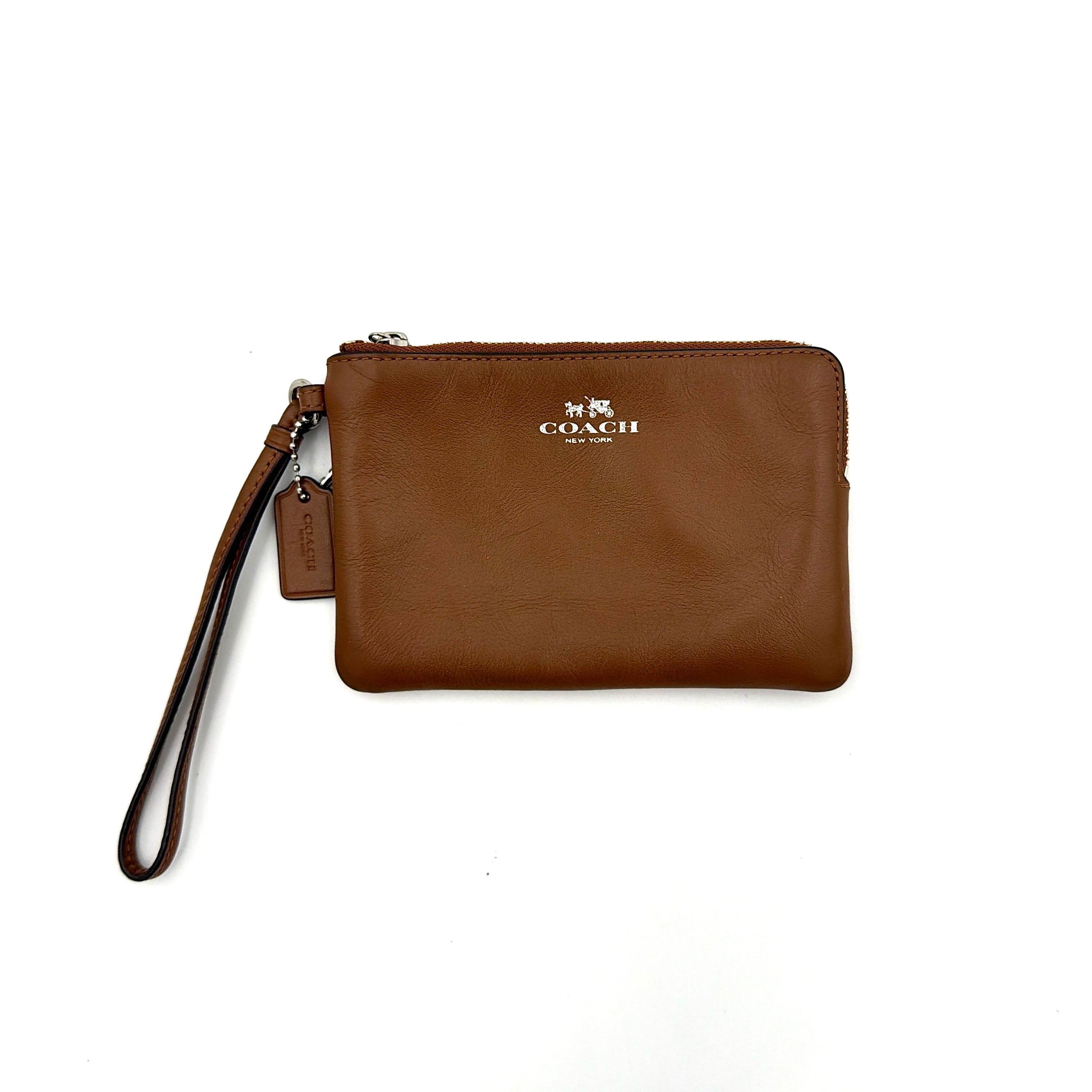 Coach Corner Zip Wristlet in smooth brown leather with silver logo and detachable wrist strap shown against a clean background.