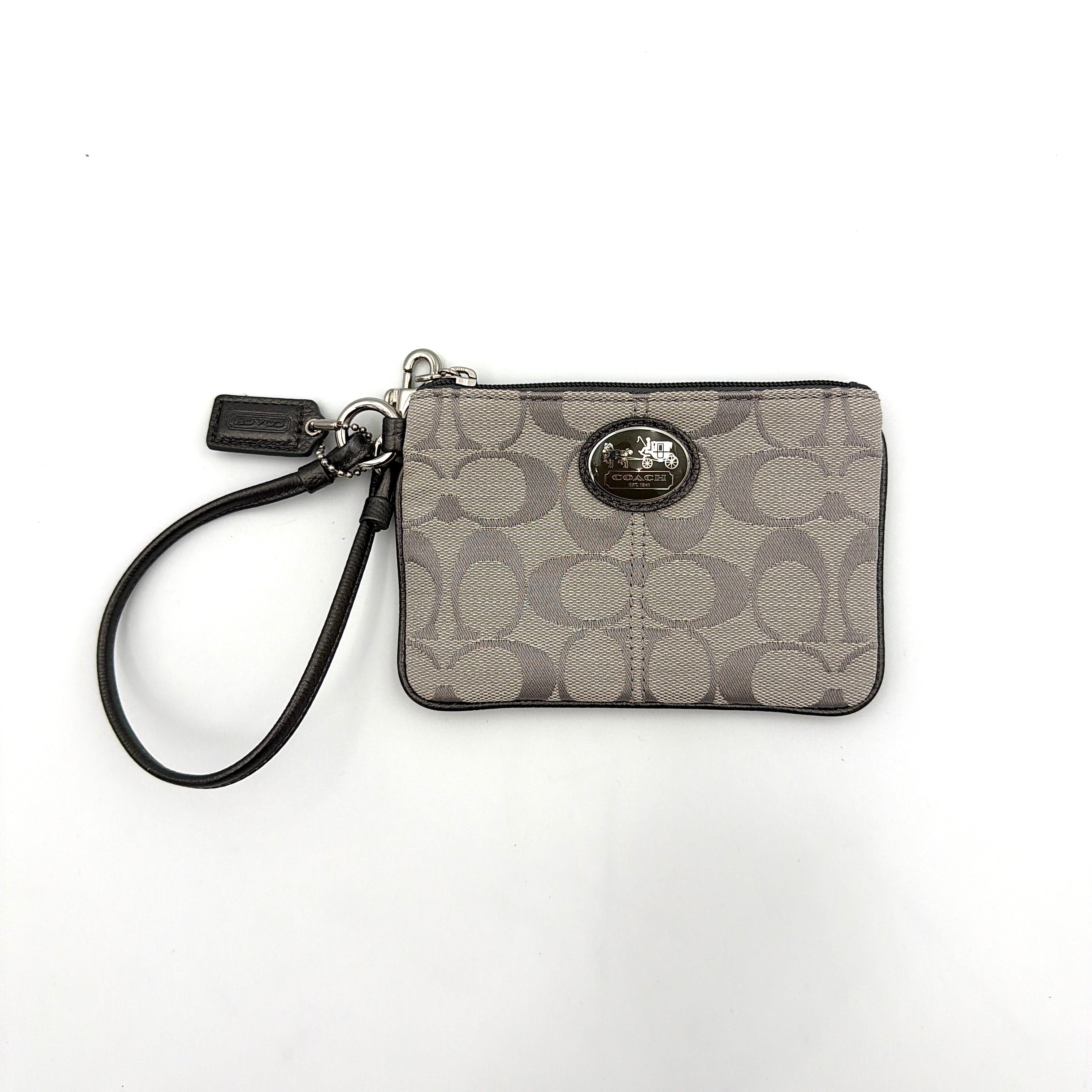 Coach Signature Canvas Corner Zip Wristlet in grey with monogram print, silver oval logo plaque, and black leather wrist strap.