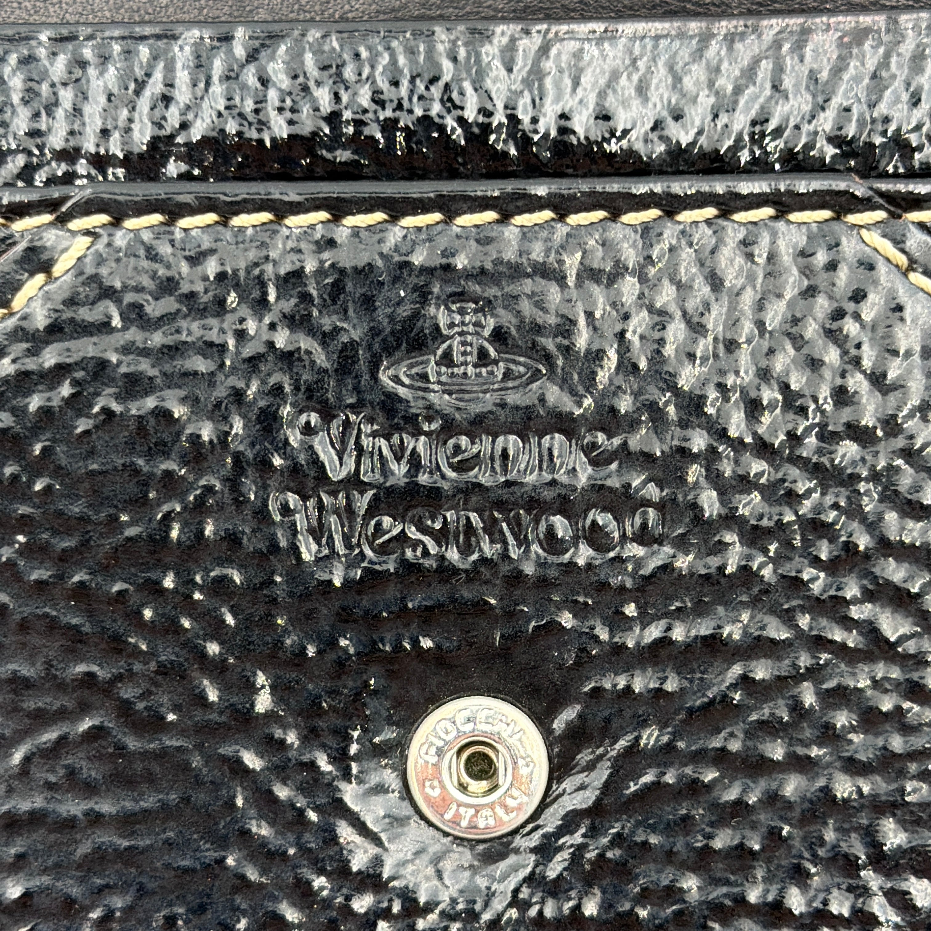 Vivienne Westwood black patent wallet featuring a silver heart orb emblem and envelope flap design.