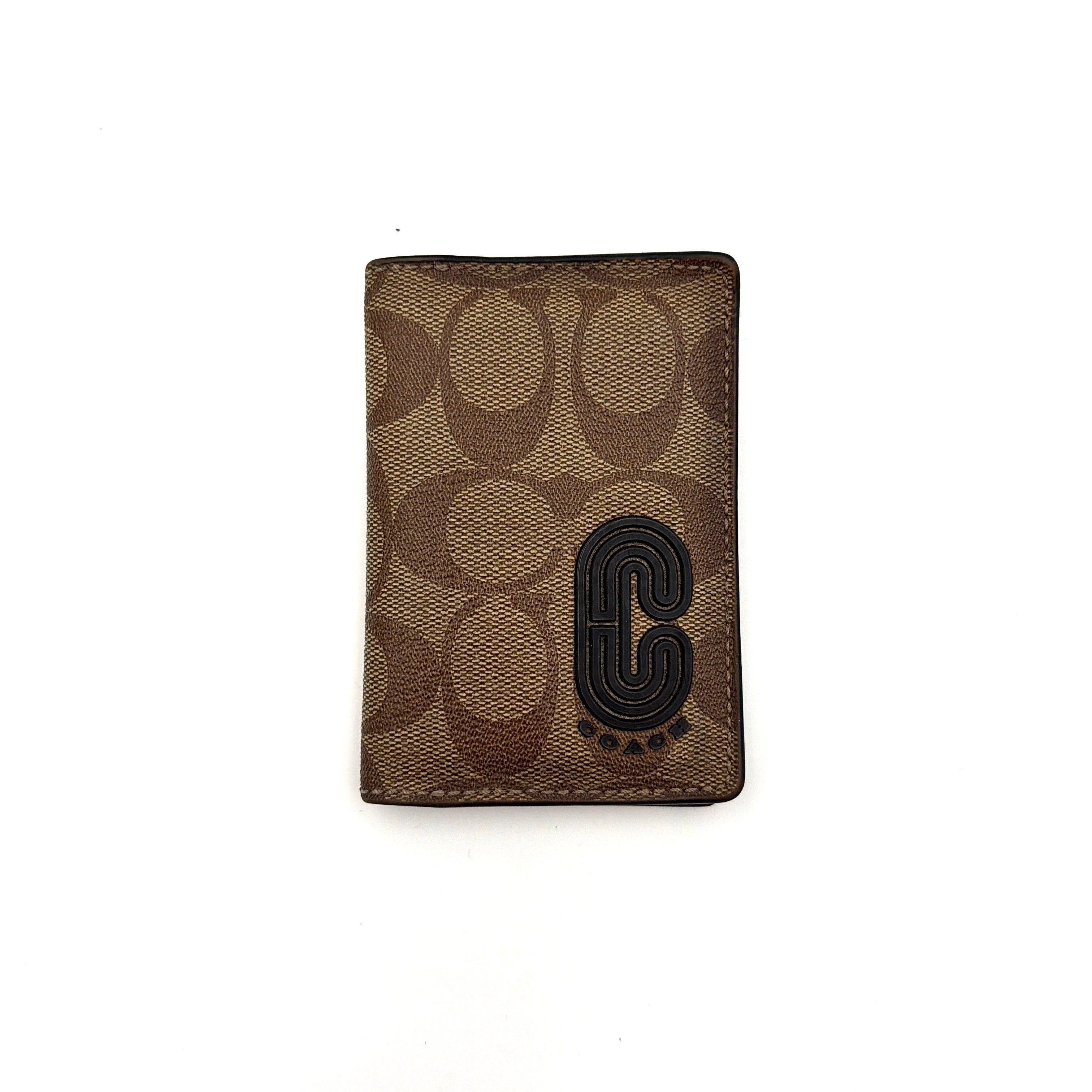 Coach Signature Canvas Patch Card Wallet in beige canvas with bold black logo patch, displayed closed against a white background.