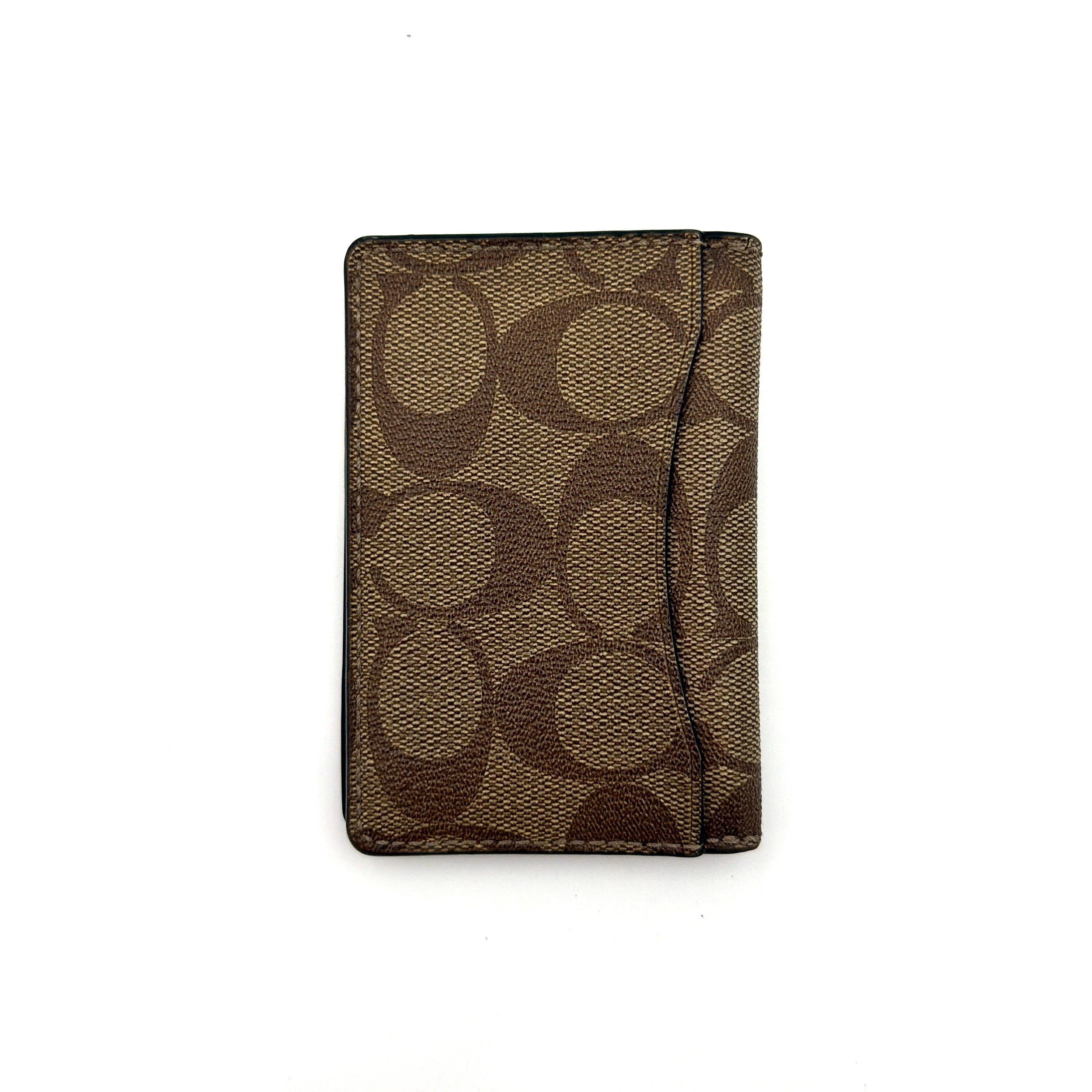 Coach Signature Canvas Patch Card Wallet in beige canvas with bold black logo patch, displayed closed against a white background.