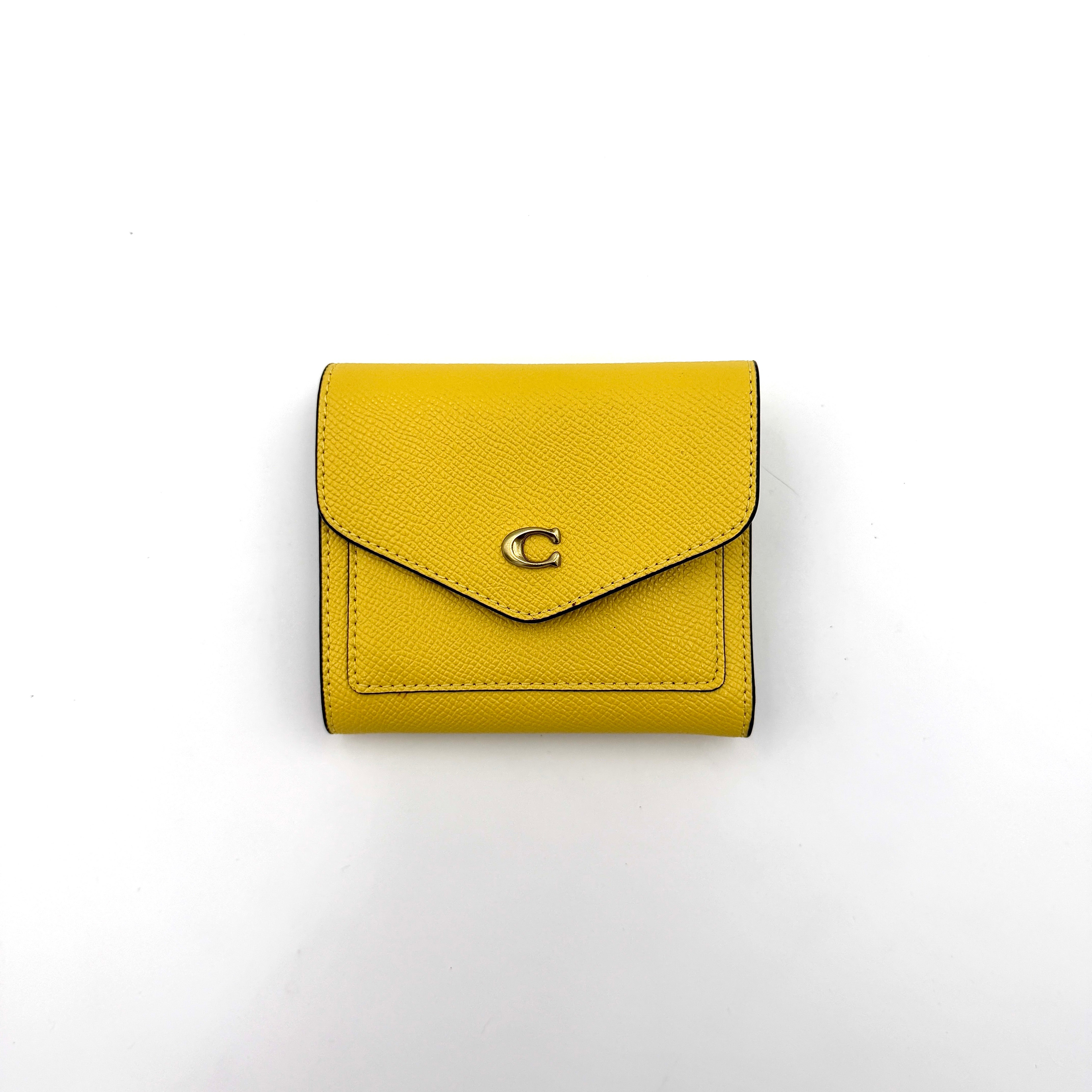 Coach Wyn Small Wallet in vibrant yellow leather with gold-tone 'C' detail on the envelope flap.