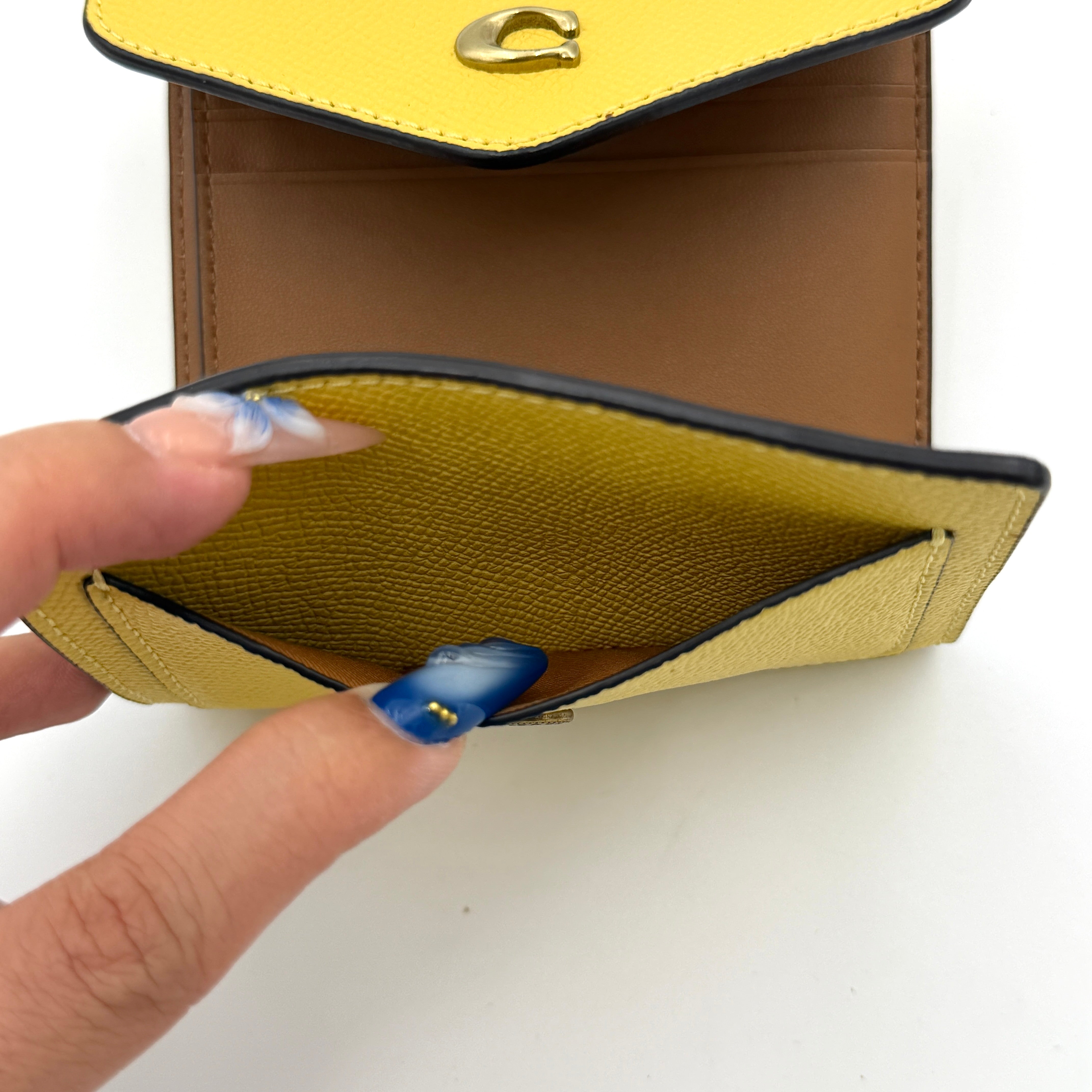 Coach Wyn Small Wallet in vibrant yellow leather with gold-tone 'C' detail on the envelope flap.
