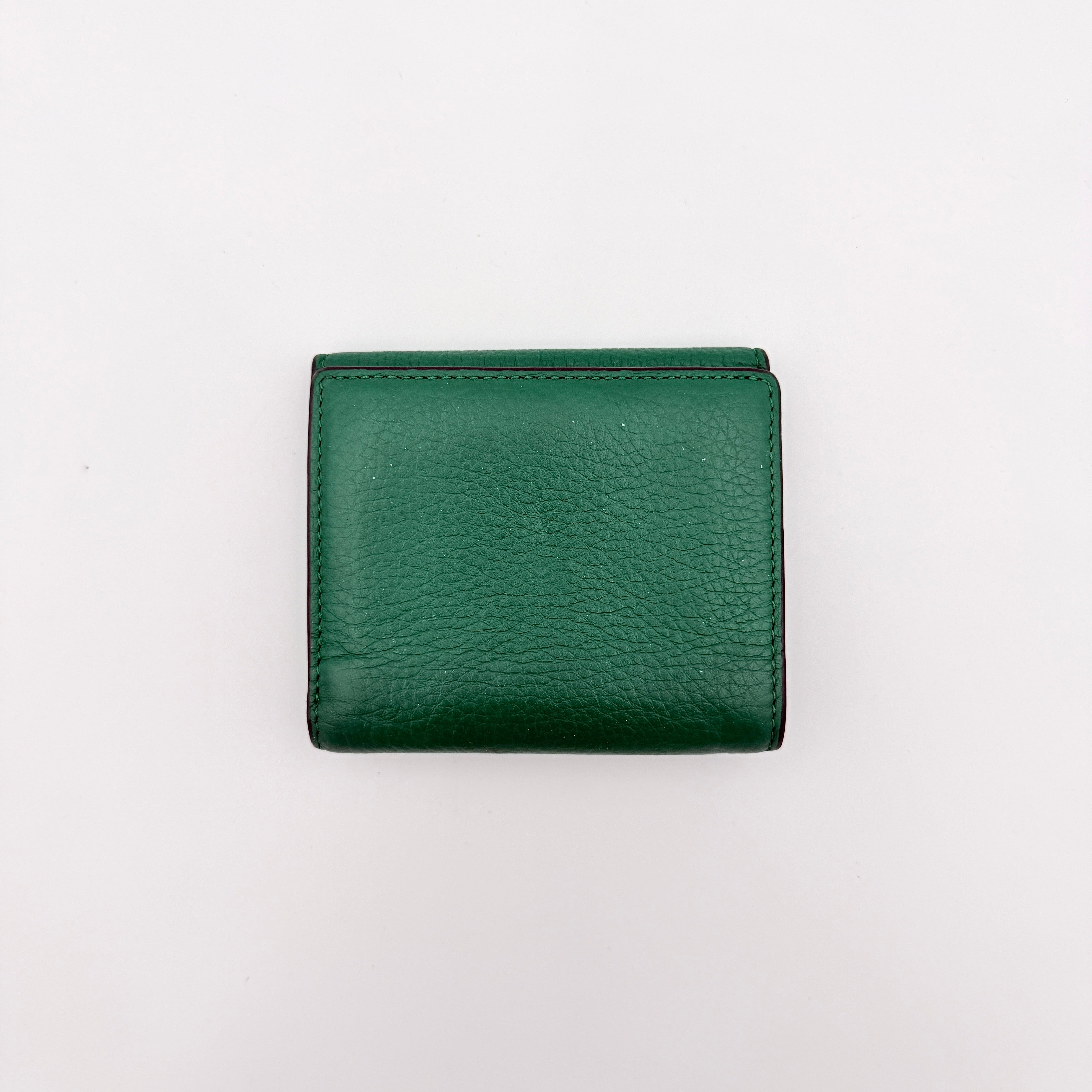 Coach Pepper Leather Wallet in emerald green pebbled leather with a front flap and enamel logo plaque, displayed neatly against a white background.