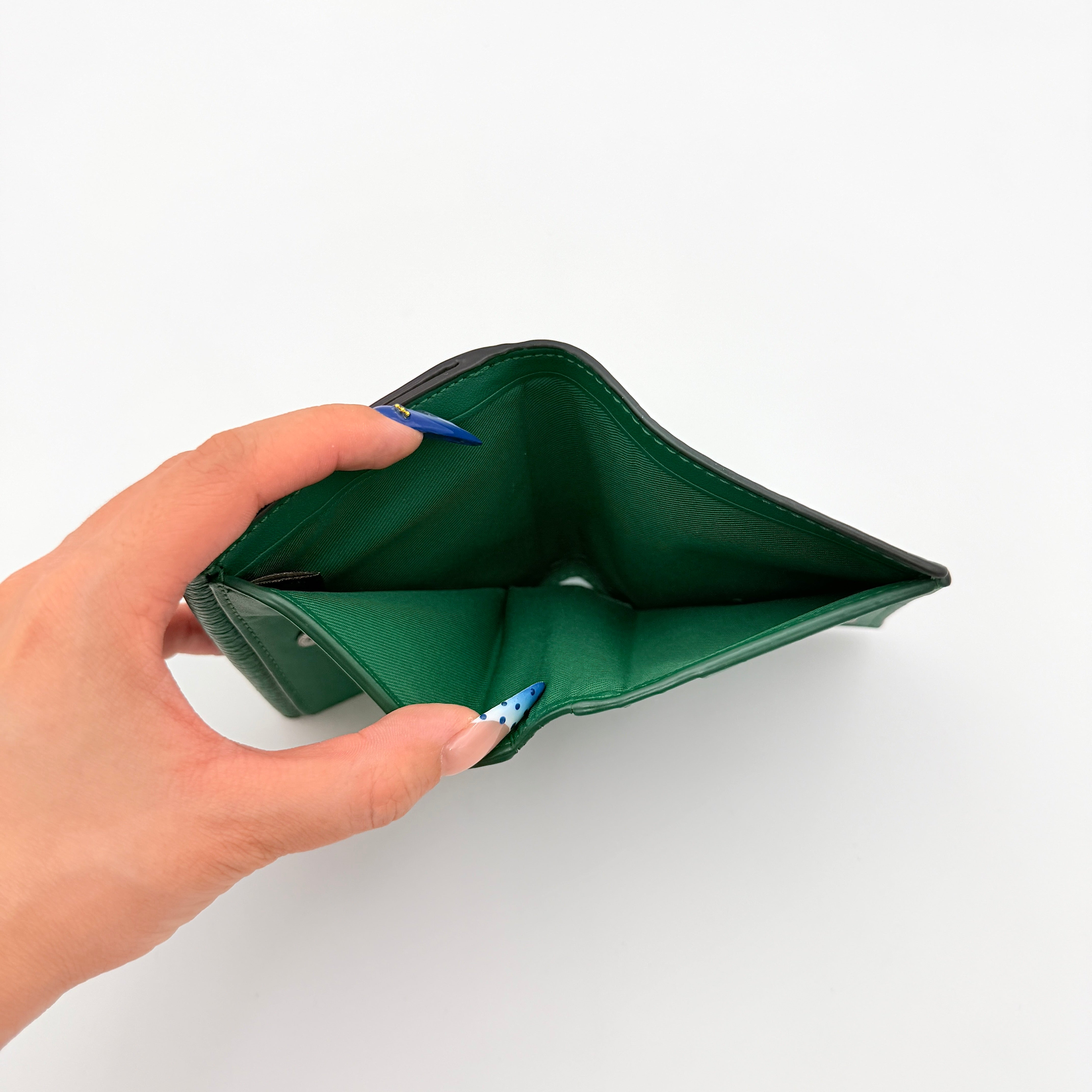 Coach Pepper Leather Wallet in emerald green pebbled leather with a front flap and enamel logo plaque, displayed neatly against a white background.