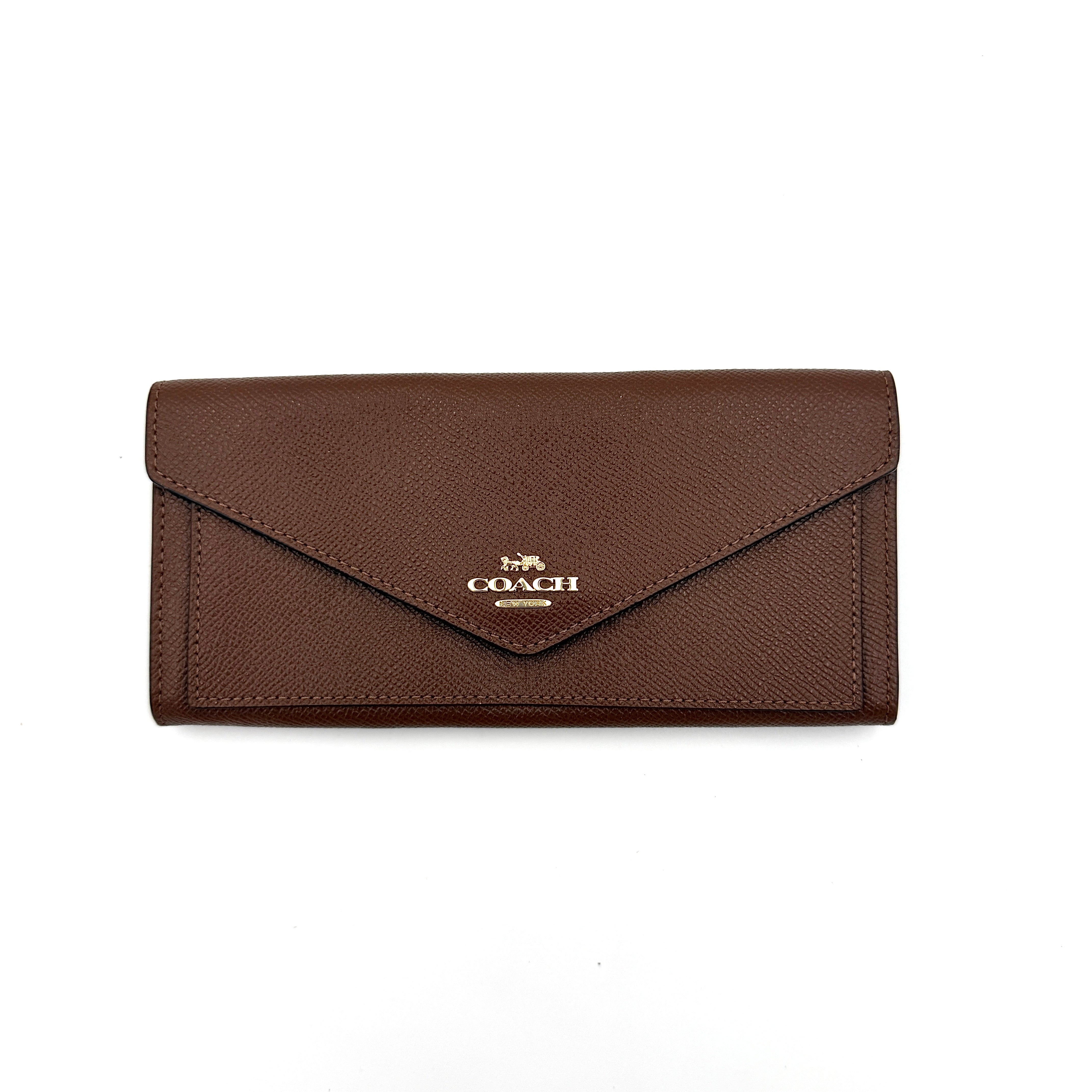 Coach brown envelope long wallet in textured leather with gold hardware, shown closed with the signature horse and carriage logo.