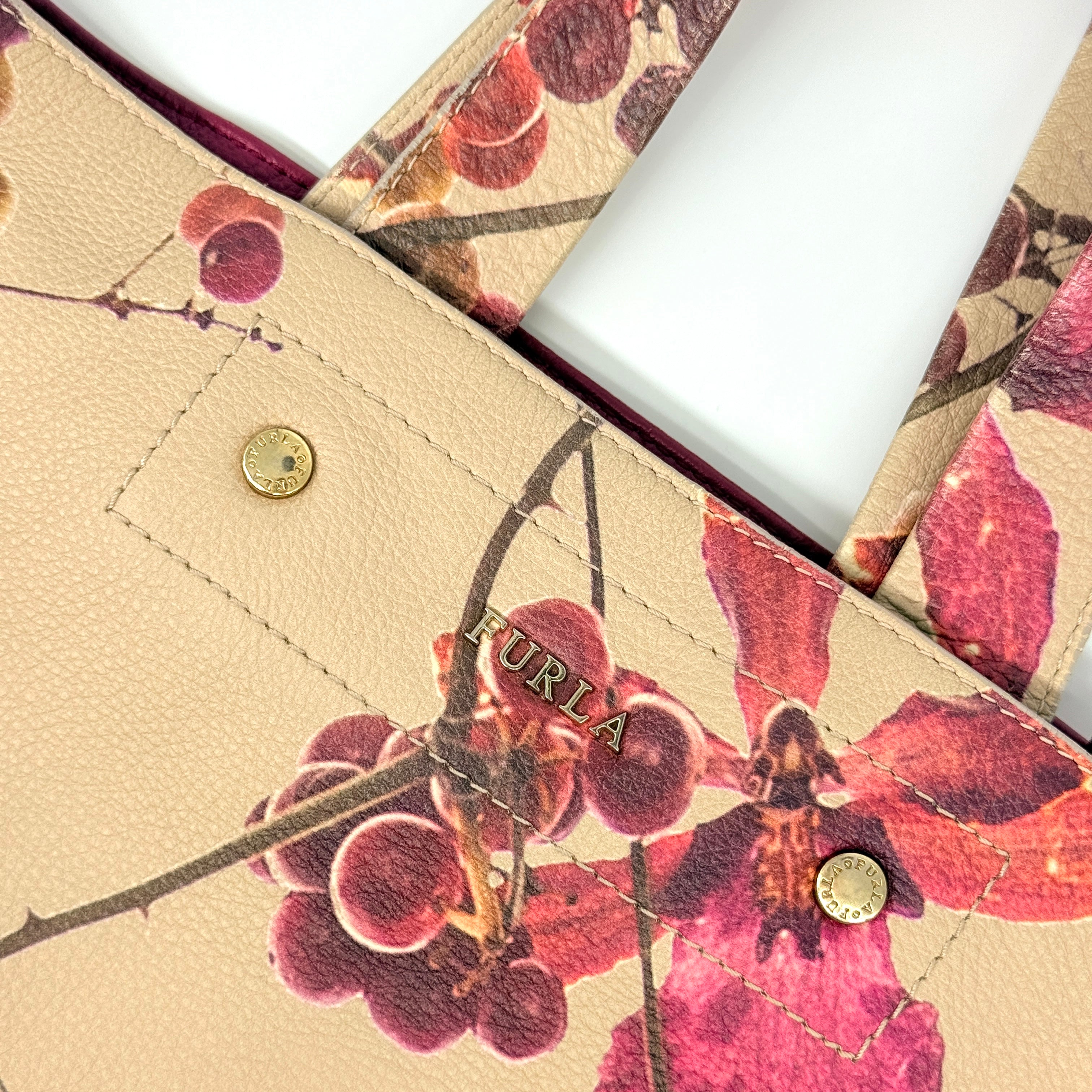 Furla beige leather tote bag adorned with a bold magenta and plum floral print, featuring structured short handles.