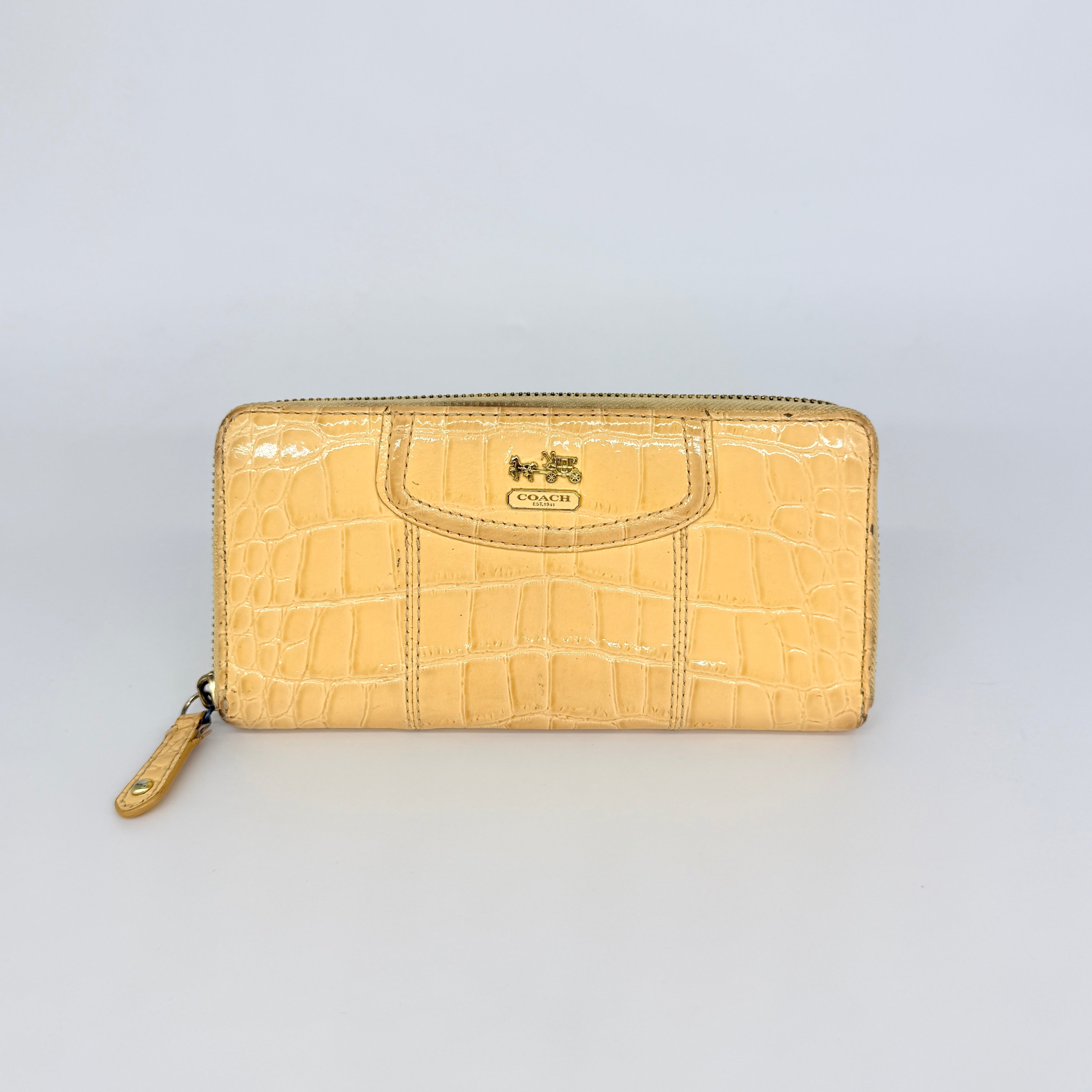 Coach beige croc-embossed zip around wallet with gold hardware and a sleek, structured silhouette.