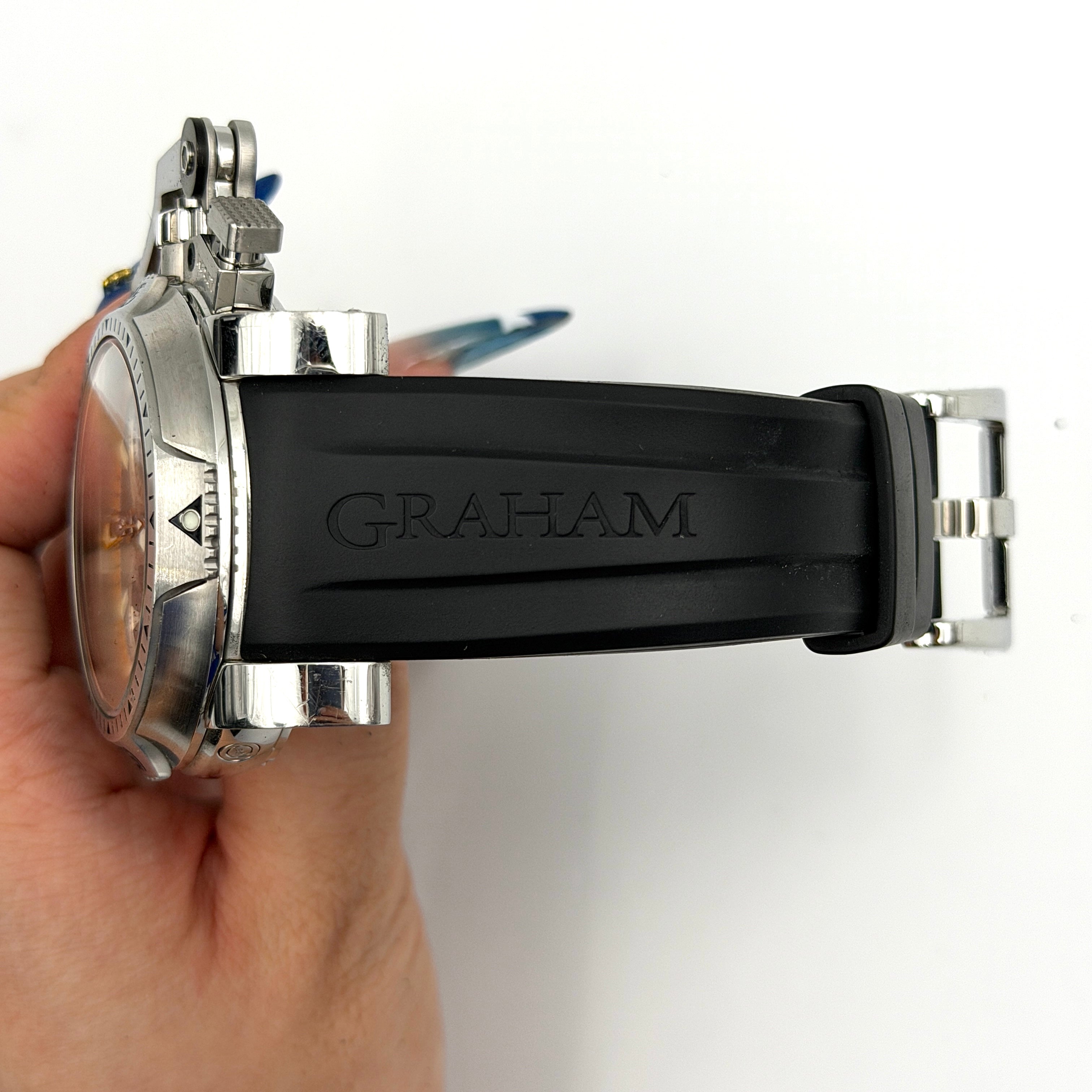 The Graham Chronofighter Oversize Diver 2OVES.B15A watch displayed in its signature round Graham London presentation case, showcasing its bold black dial, prominent chronograph trigger, and black rubber strap.