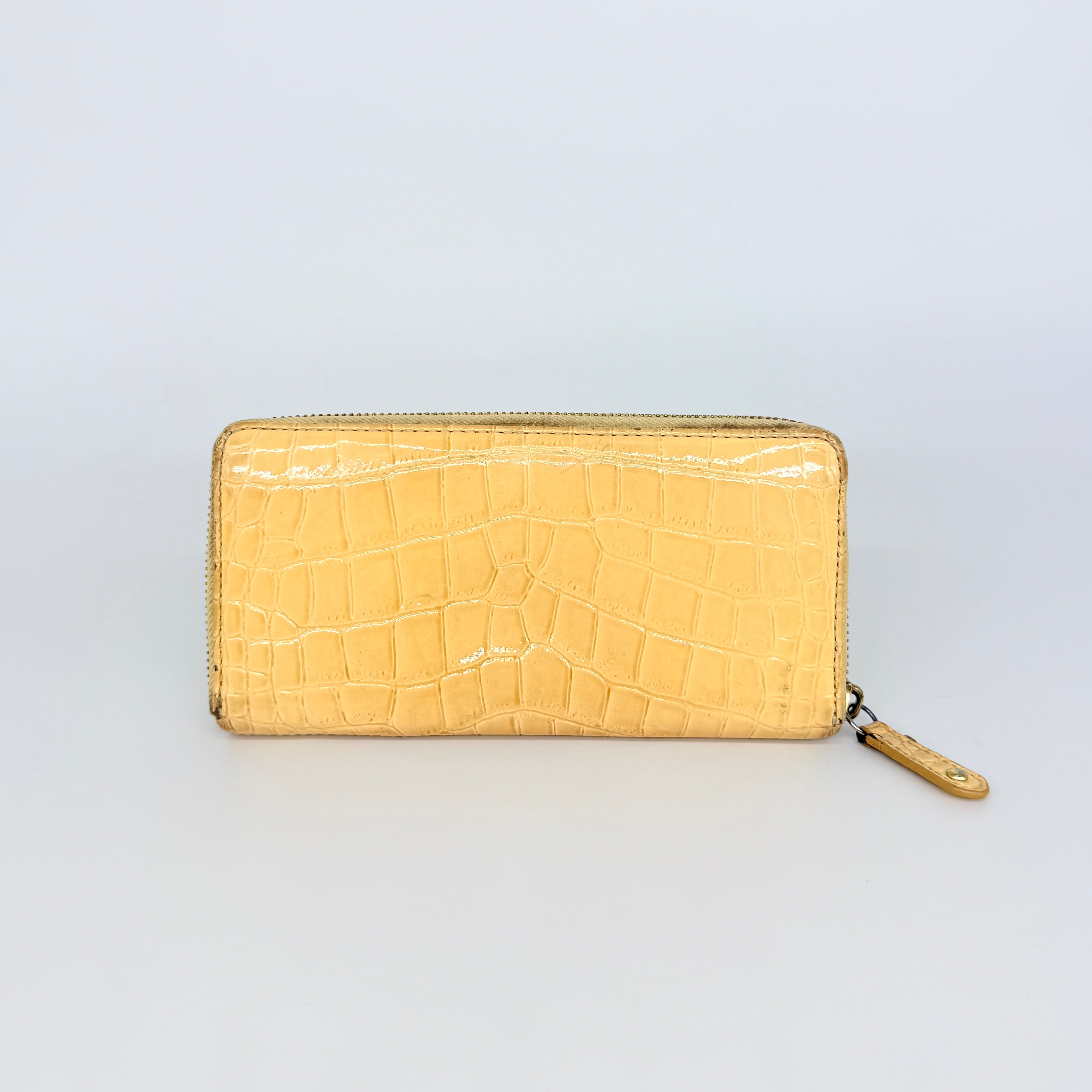 Coach beige croc-embossed zip around wallet with gold hardware and a sleek, structured silhouette.