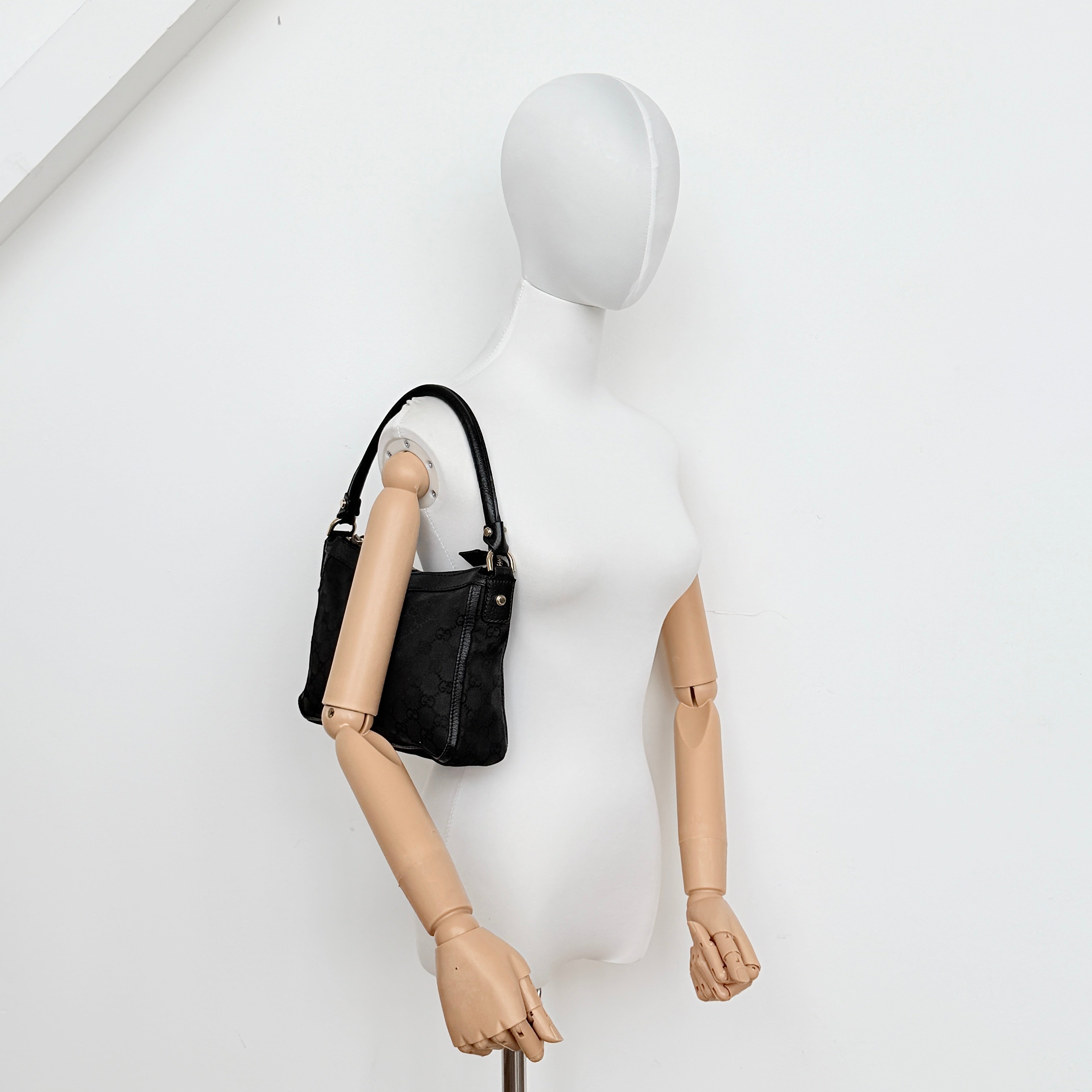 Front view of the Gucci GG Monogram Abbey Shoulder Bag in black with curved handle and gold hardware.