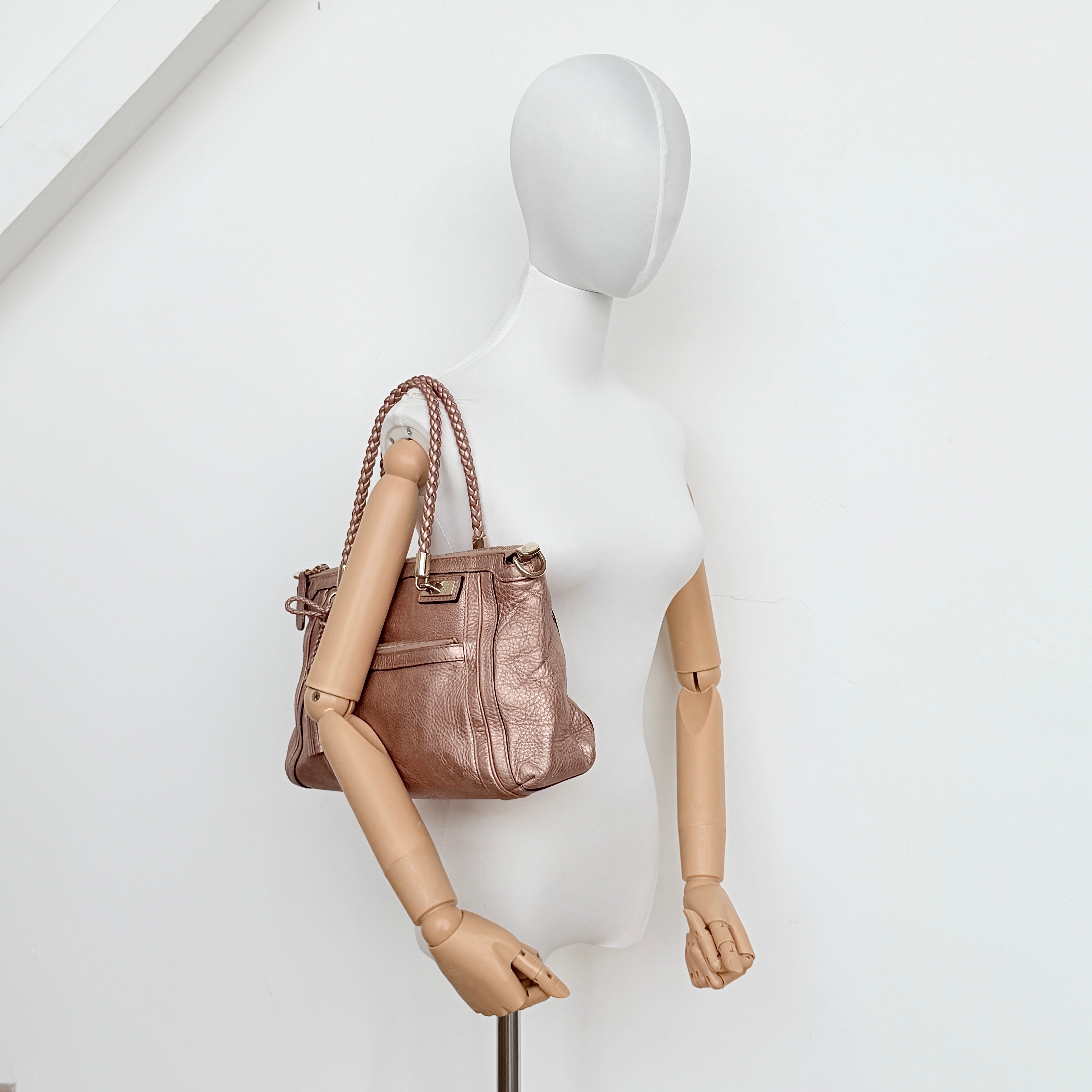 Gucci Bella Bamboo 2Way shoulder bag in metallic pink leather with braided handles and bamboo tassel accents, displayed with a detachable strap.