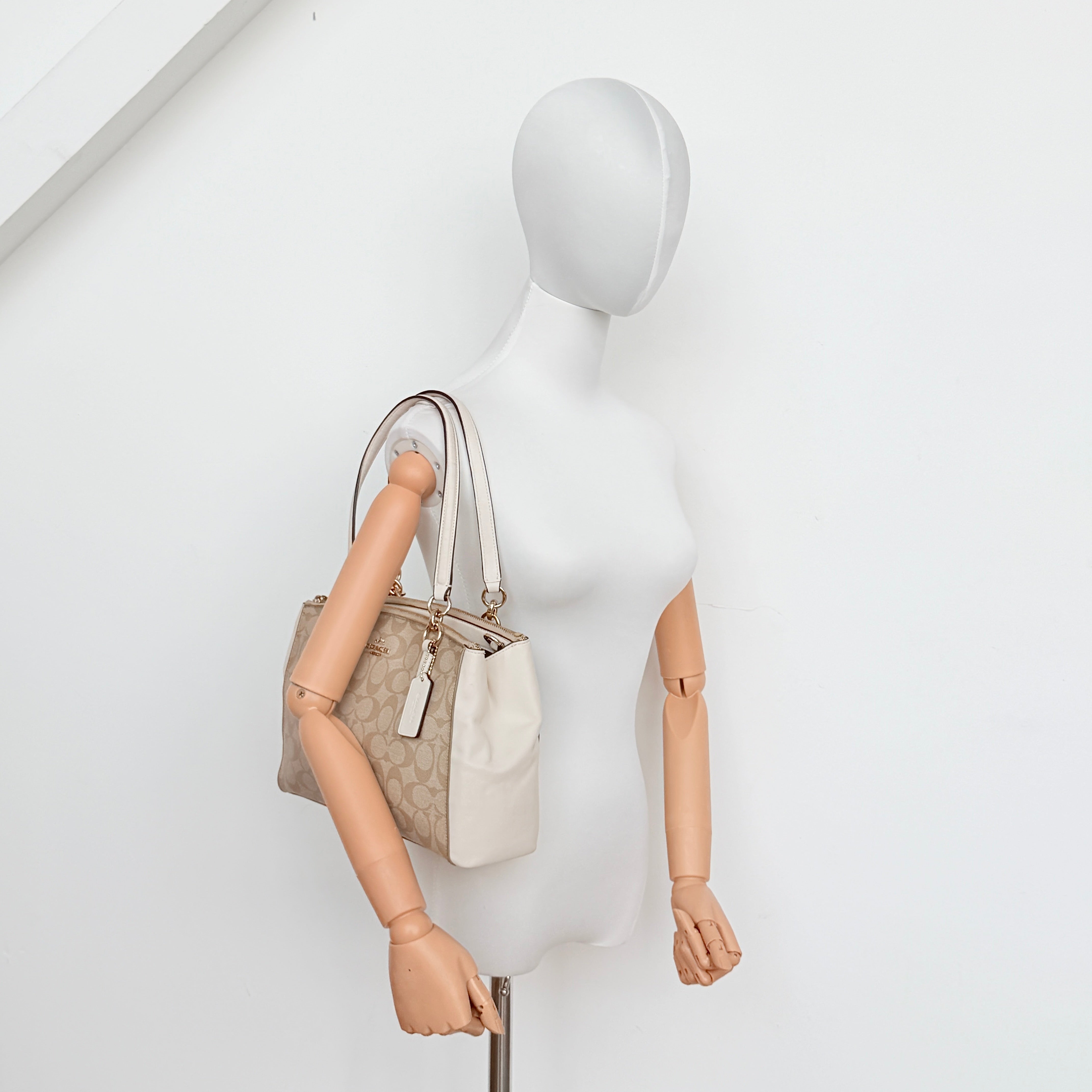 Coach Signature Christie Carryall in beige jacquard with white leather panels, double handles, and detachable strap.