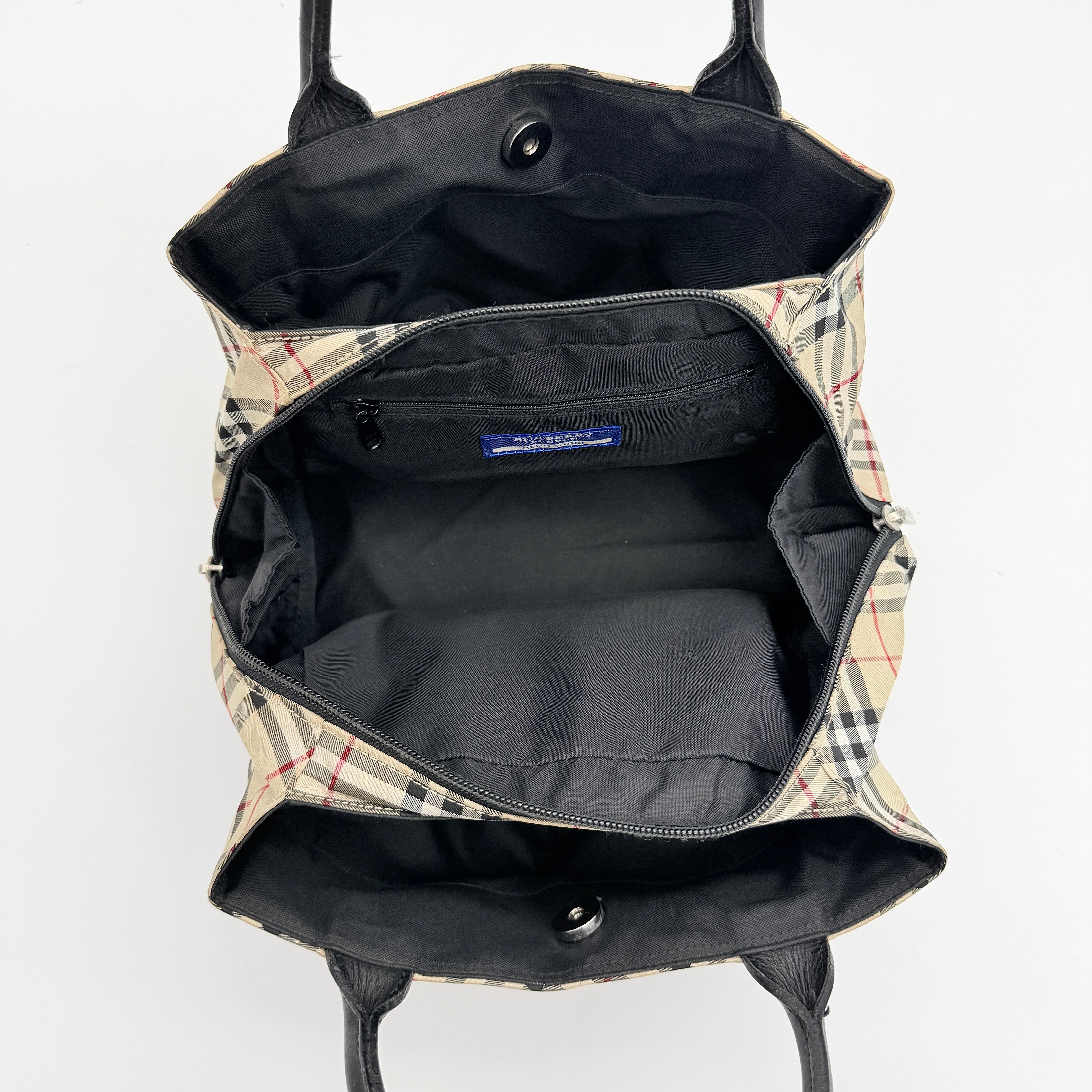 Burberry Blue Label Nova Check nylon shoulder bag in beige and black with leather handles, displayed against a white background.