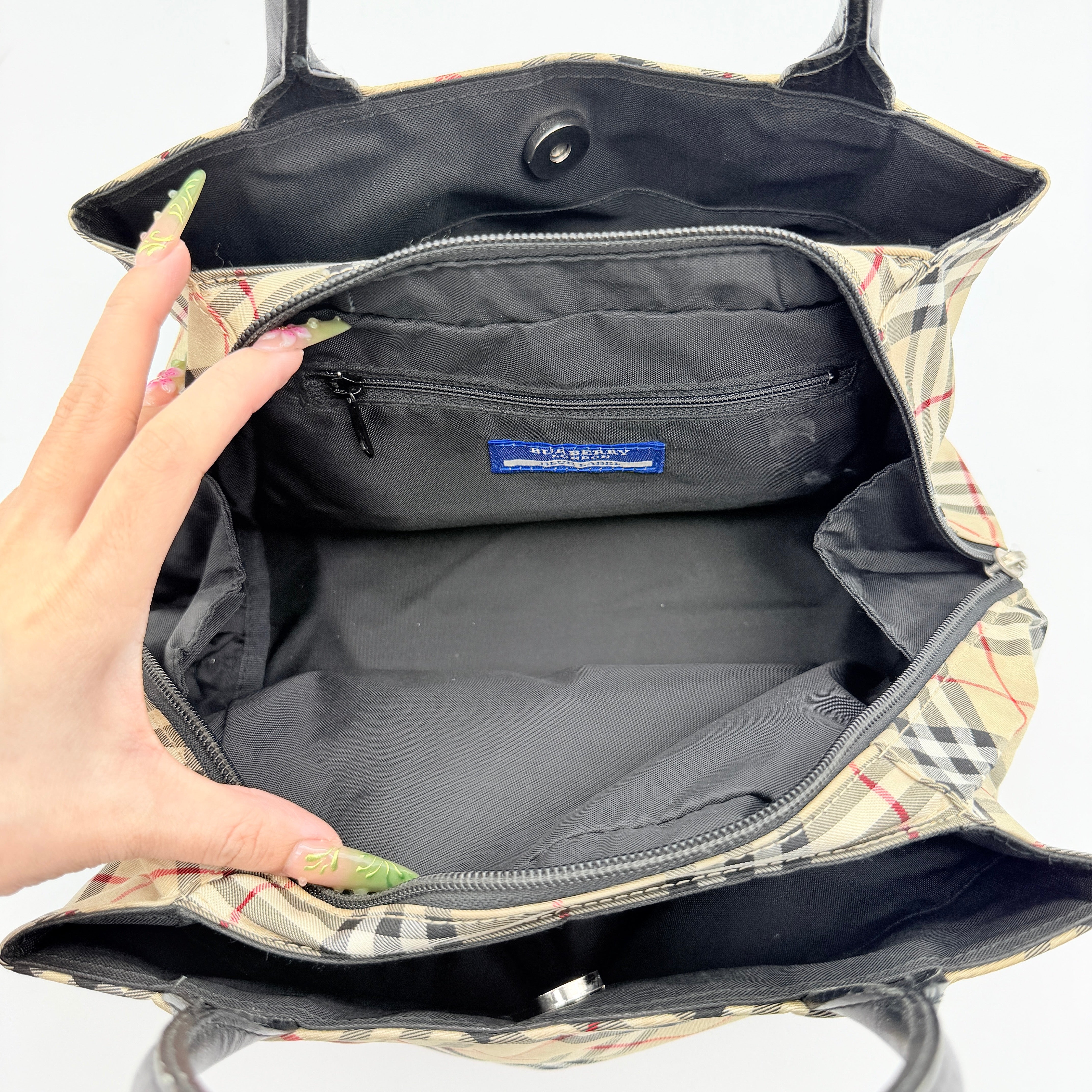 Burberry Blue Label Nova Check nylon shoulder bag in beige and black with leather handles, displayed against a white background.