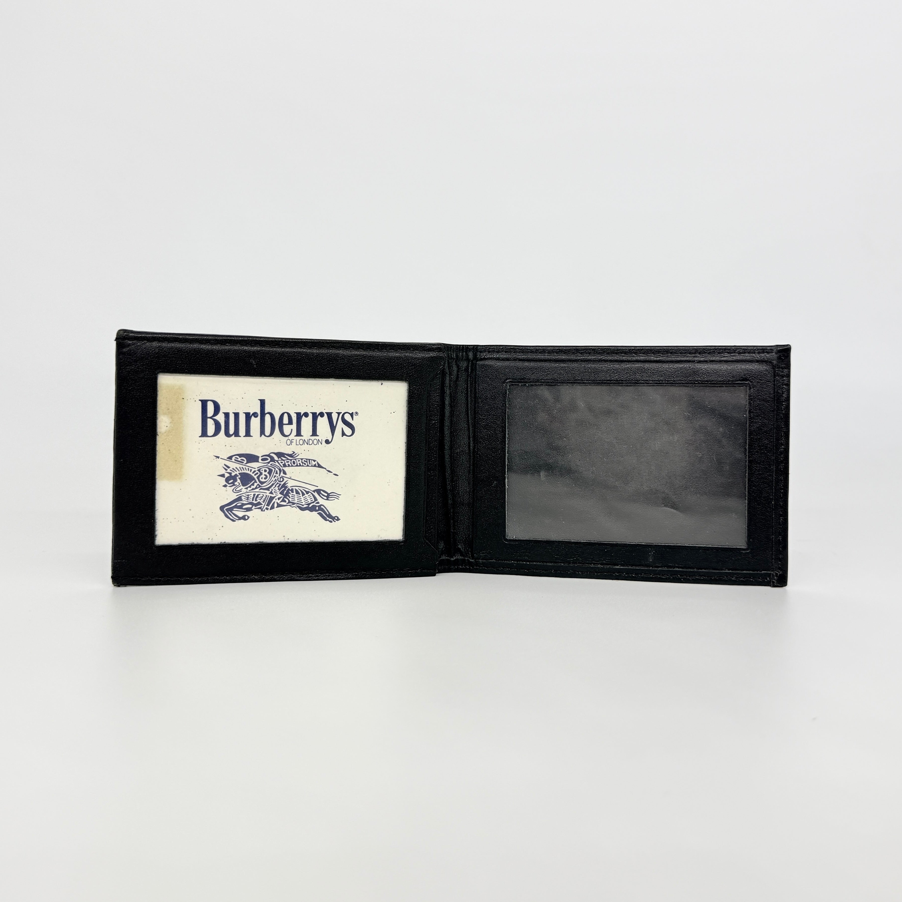 Front-facing view of a Burberry Nova Check cardholder in beige canvas with black leather trim and an oval Burberrys plaque.