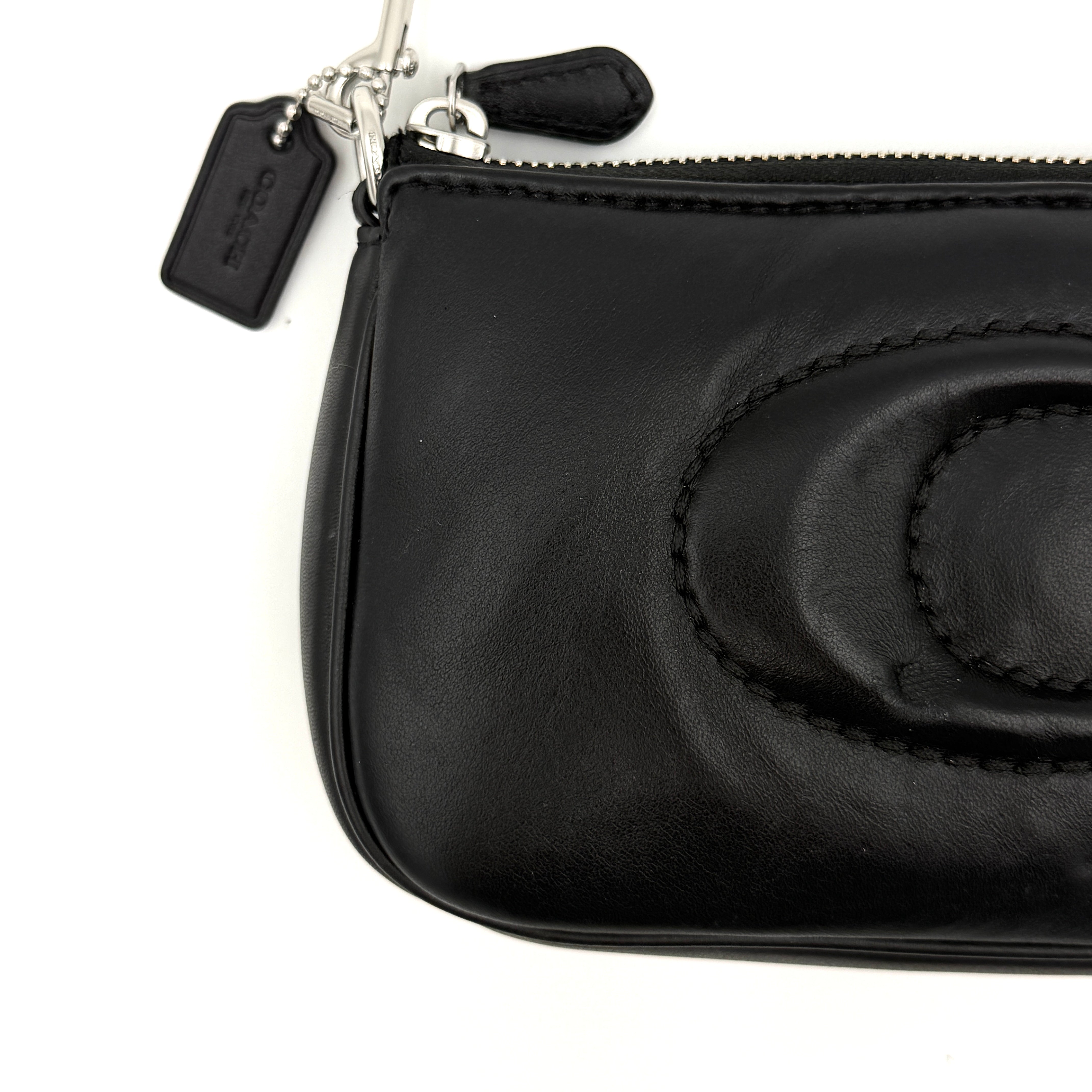Coach Nolita 19 shoulder bag in quilted black leather with a bold stitched 'C' emblem and chunky silver chain strap.